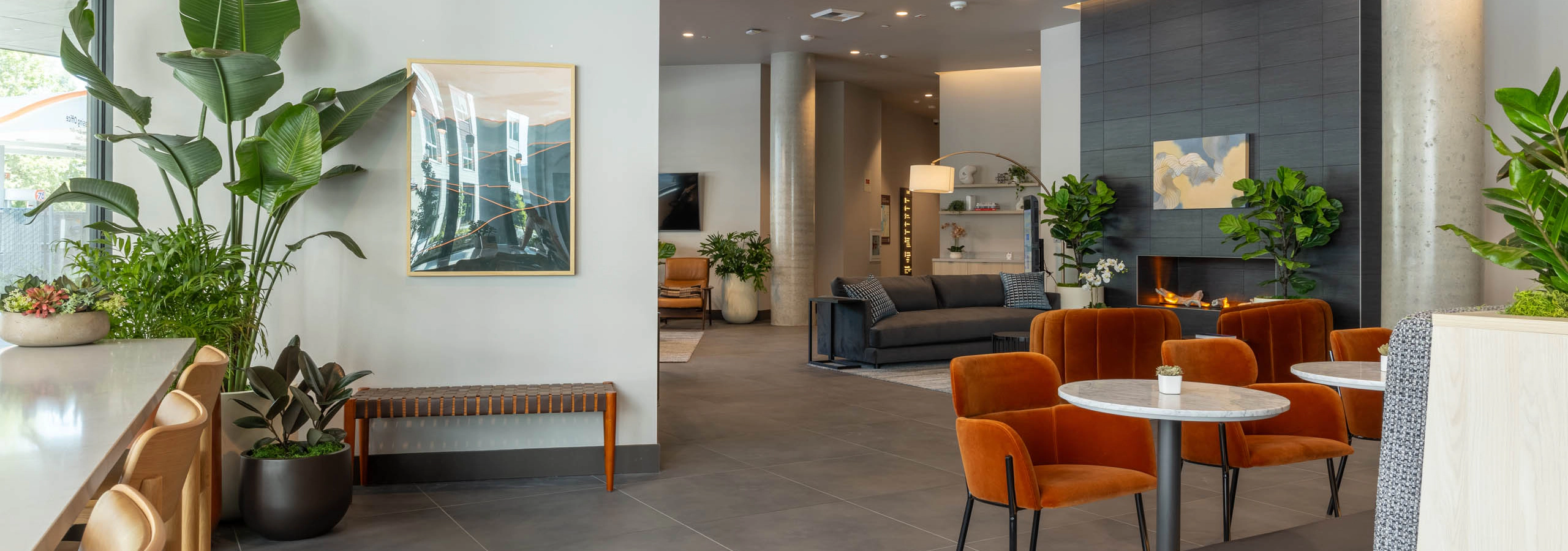 East Building lobby with seating areas, a fireplace lounge, artwork, and greenery throughout the open, modern space.