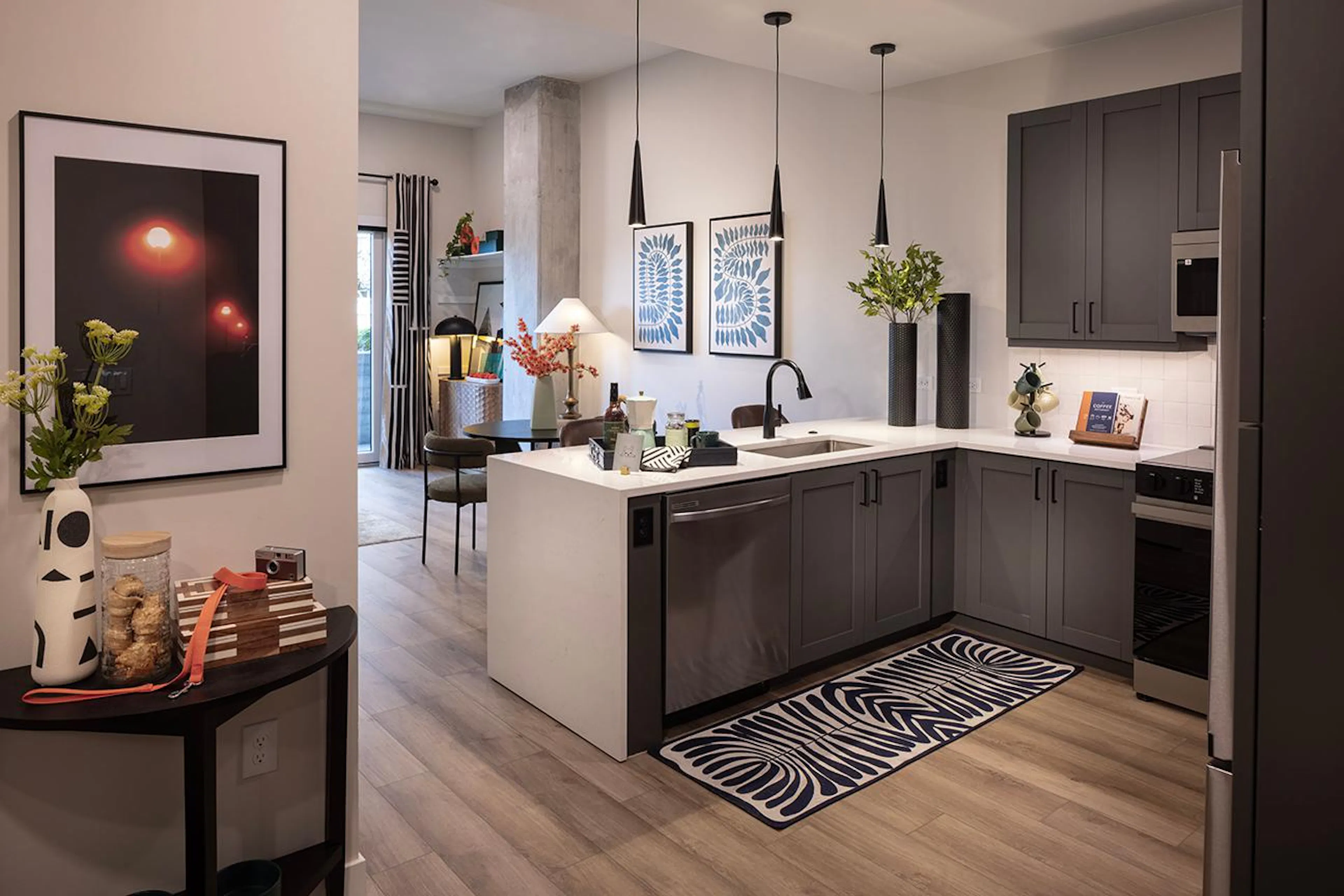 A cozy kitchen at AMLI Golden Triangle with a black and white patterned rug below the sleek grey kitchen cabinets