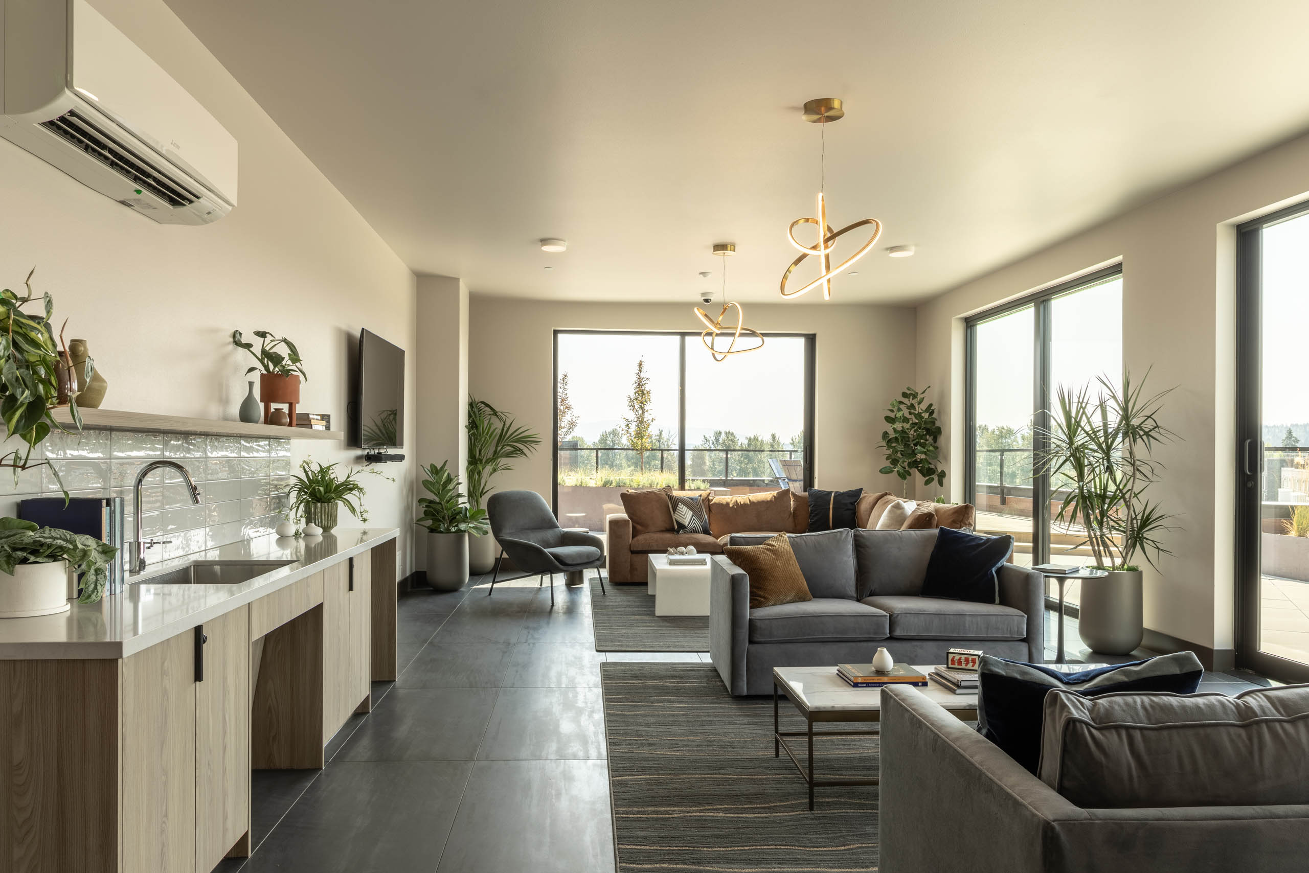Overlook Club lounge with a kitchenette, sectional and lounge seating, decorative lighting, and floor-to-ceiling windows overlooking an outdoor terrace.