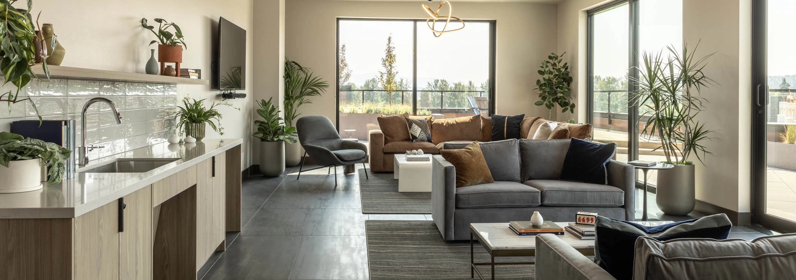 Overlook Club lounge with a kitchenette, sectional and lounge seating, decorative lighting, and floor-to-ceiling windows overlooking an outdoor terrace.