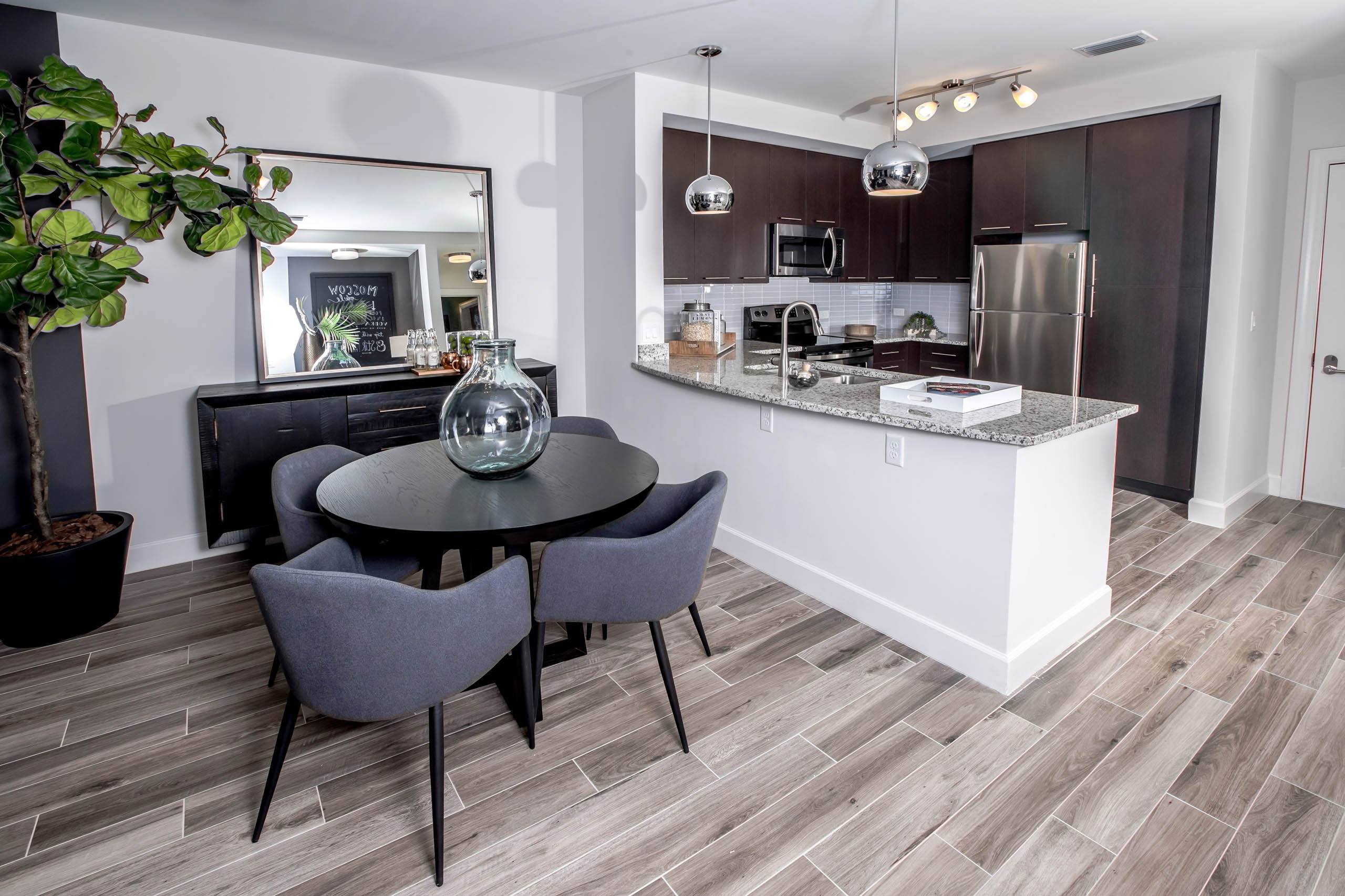 Living area at AMLI Joya apartments with contemporary decor, teal sofa with accent pillows and dining table with chairs.