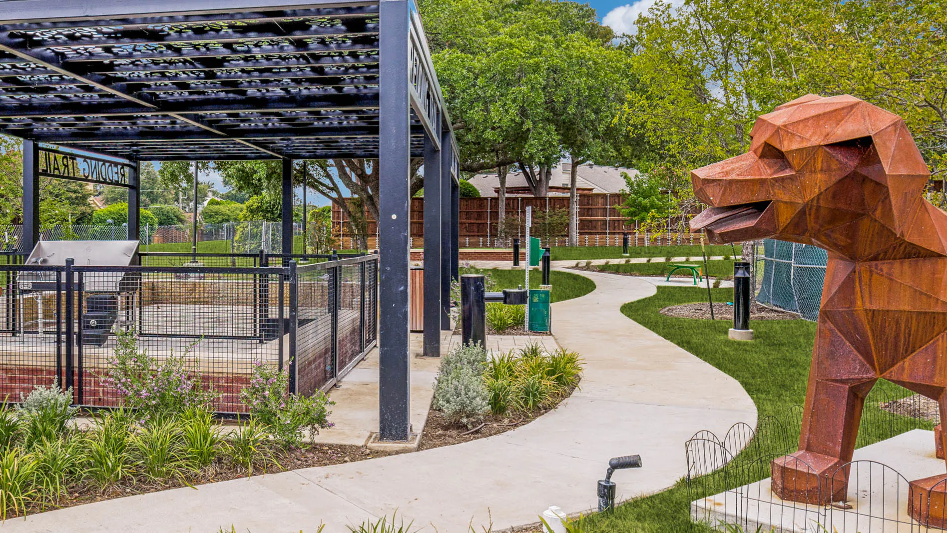 Landscaped dog park with covered pavilion, fenced play area, decorative sculptures, walking paths, and surrounding greenery at AMLI Treehouse.