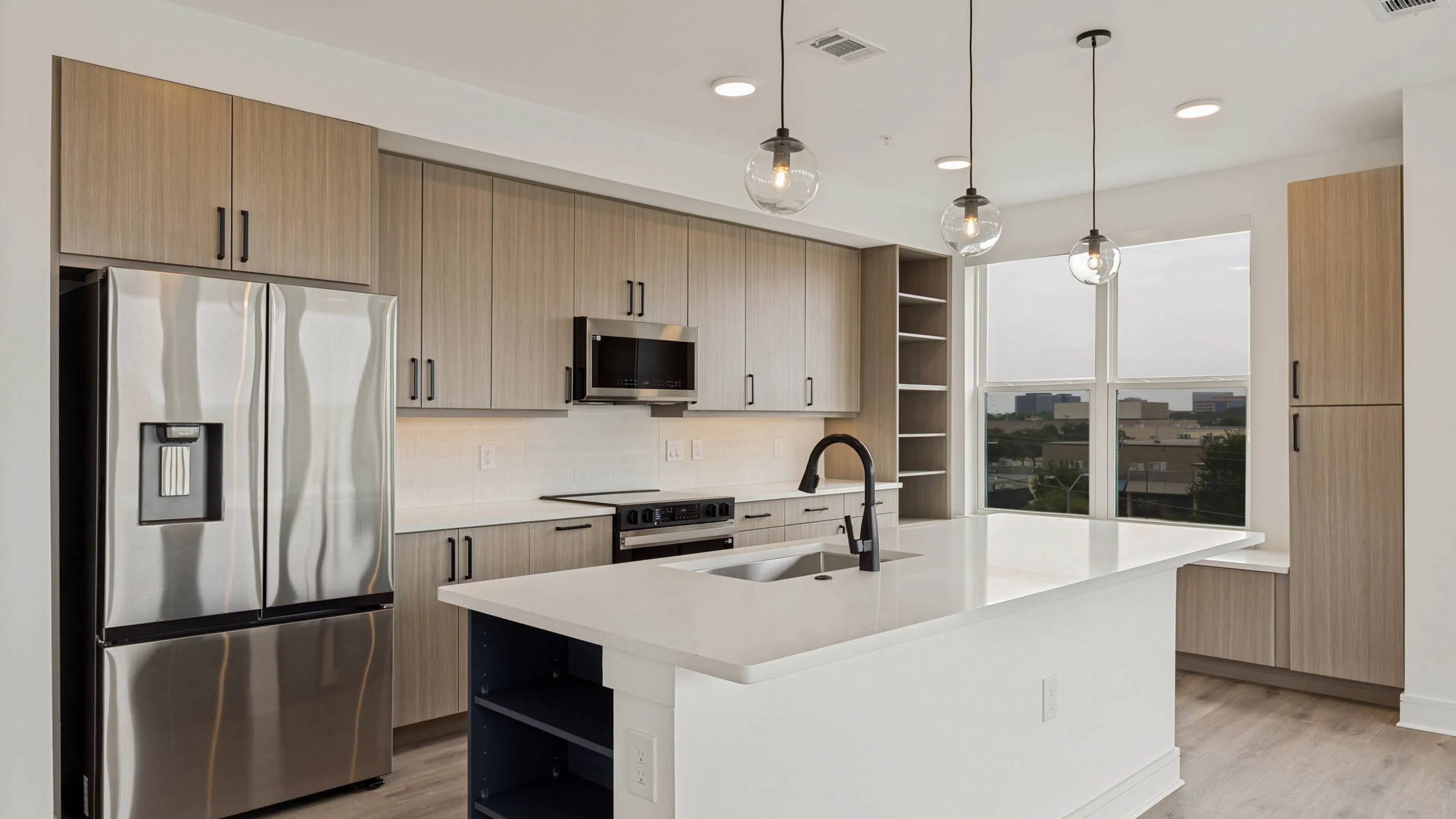 Modern kitchen with quartz island, stainless steel appliances, wood-style cabinetry, pendant lighting, open shelving, and large windows.