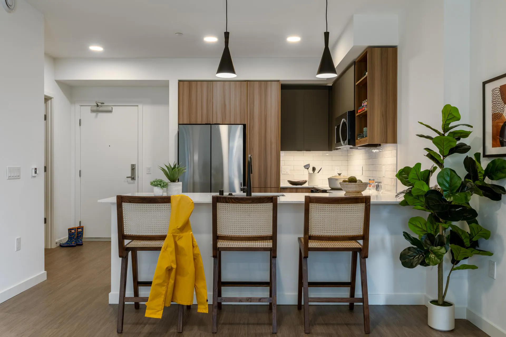 A sleek luxury apartment kitchen with stainless steel appliances and wooden cabinets and a breakfast nook with three stools