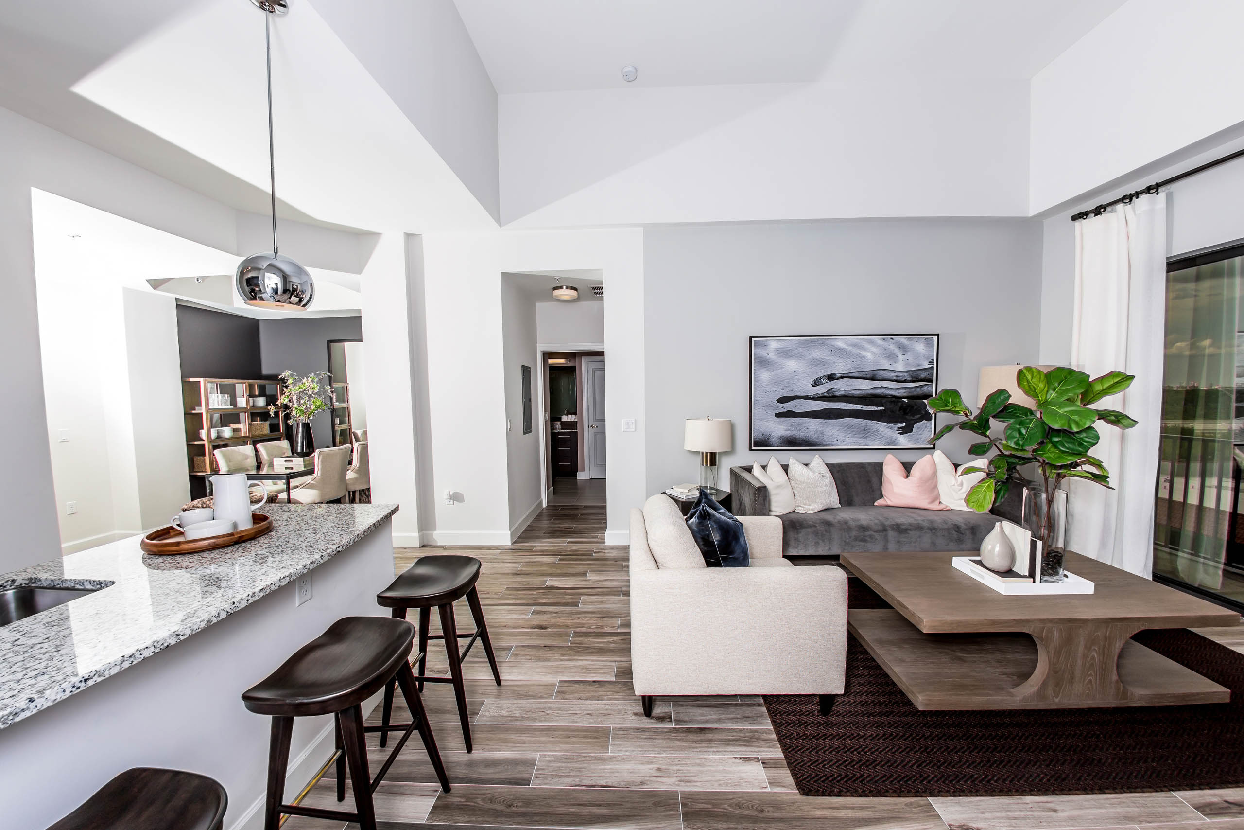  An apartment living room at AMLI Joya with cool neutral colors, a couch and coffee table and kitchen island with stools.