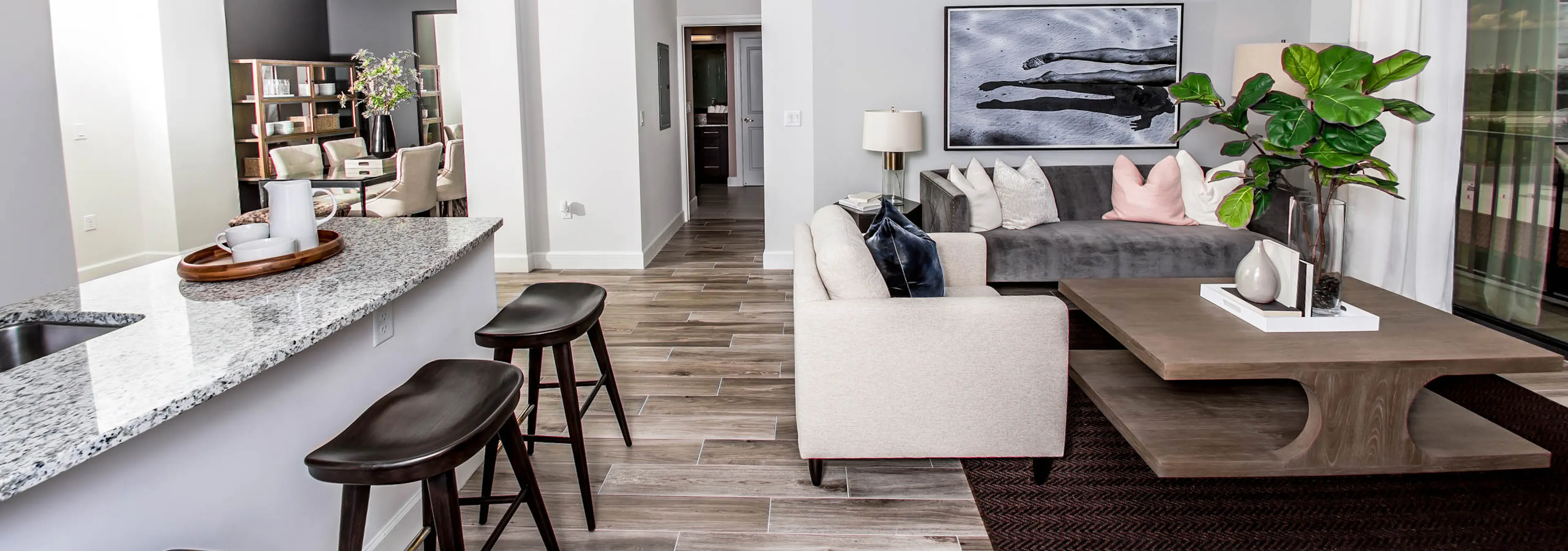  An apartment living room at AMLI Joya with cool neutral colors, a couch and coffee table and kitchen island with stools.