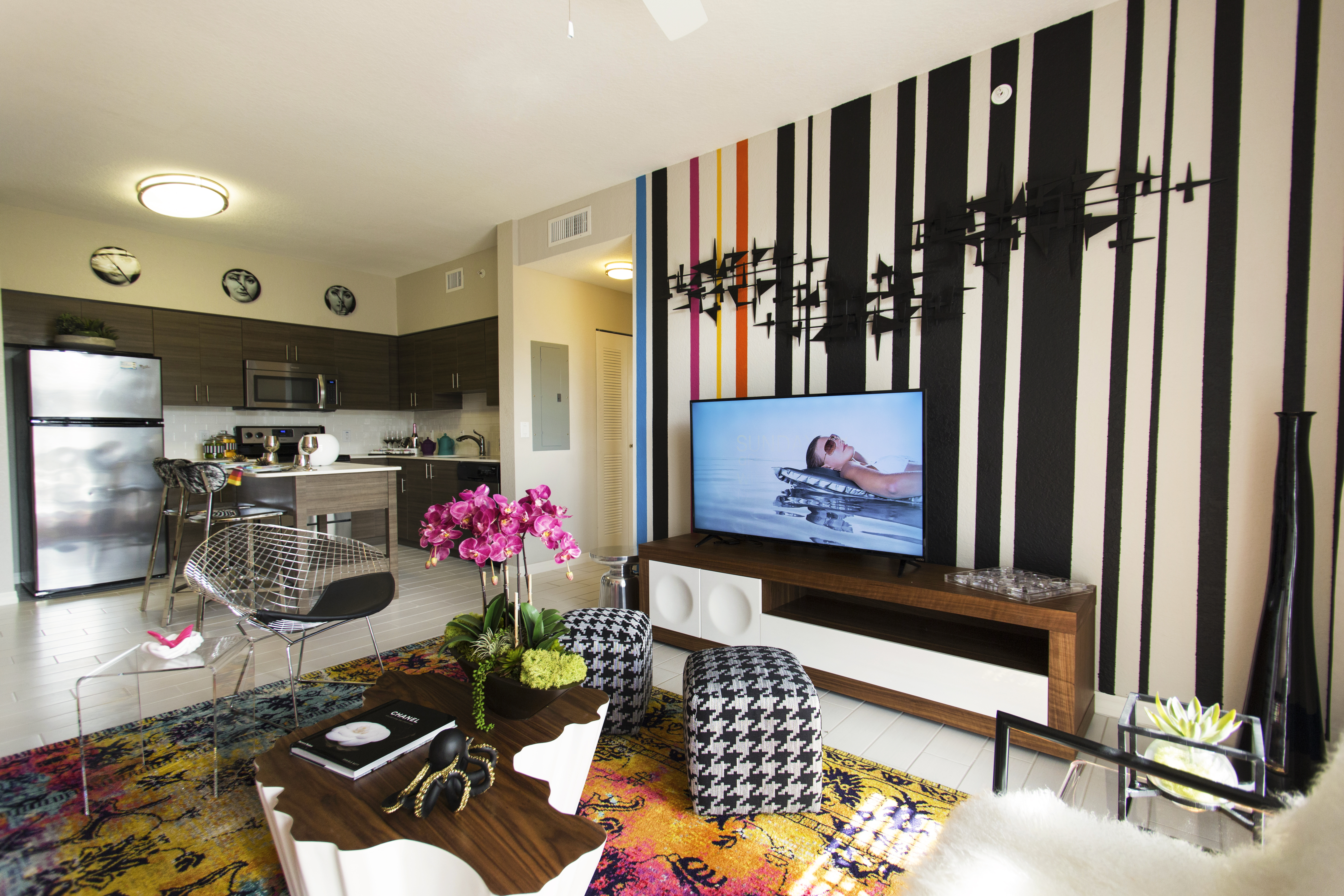 Interior of an AMLI Dadeland apartment living area with white sofa, pillows, modern colorful artwork and black floor lamps