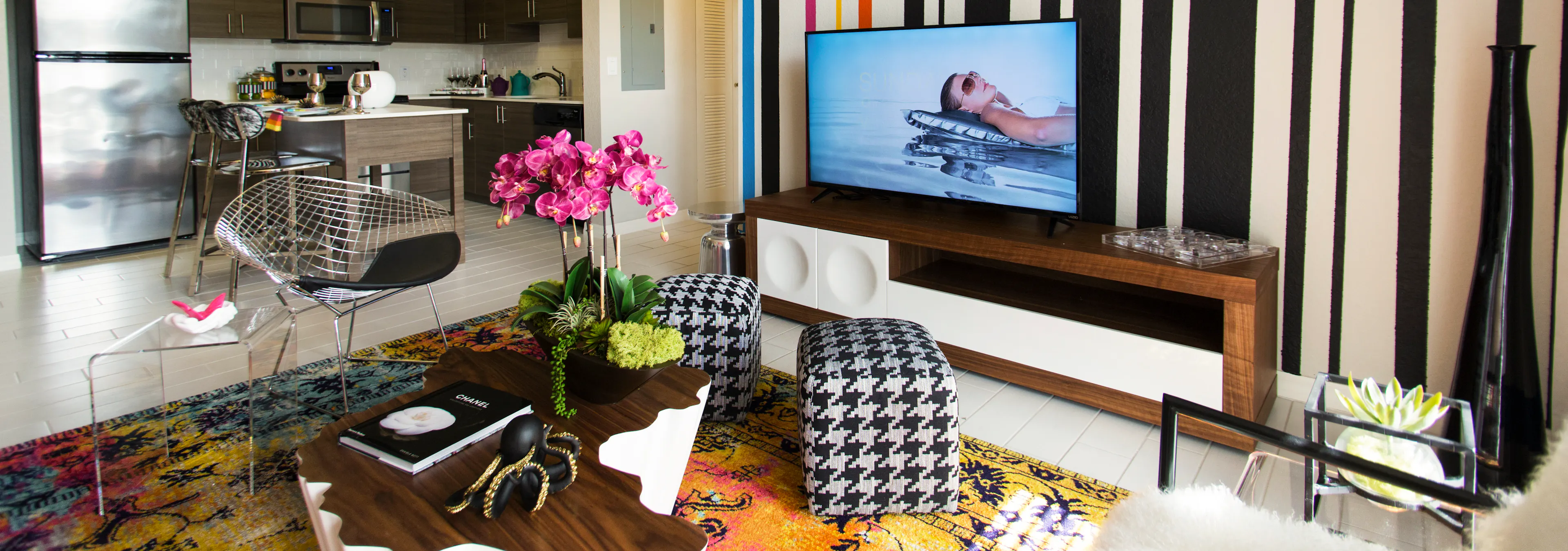 Interior of an AMLI Dadeland apartment living area with white sofa, pillows, modern colorful artwork and black floor lamps