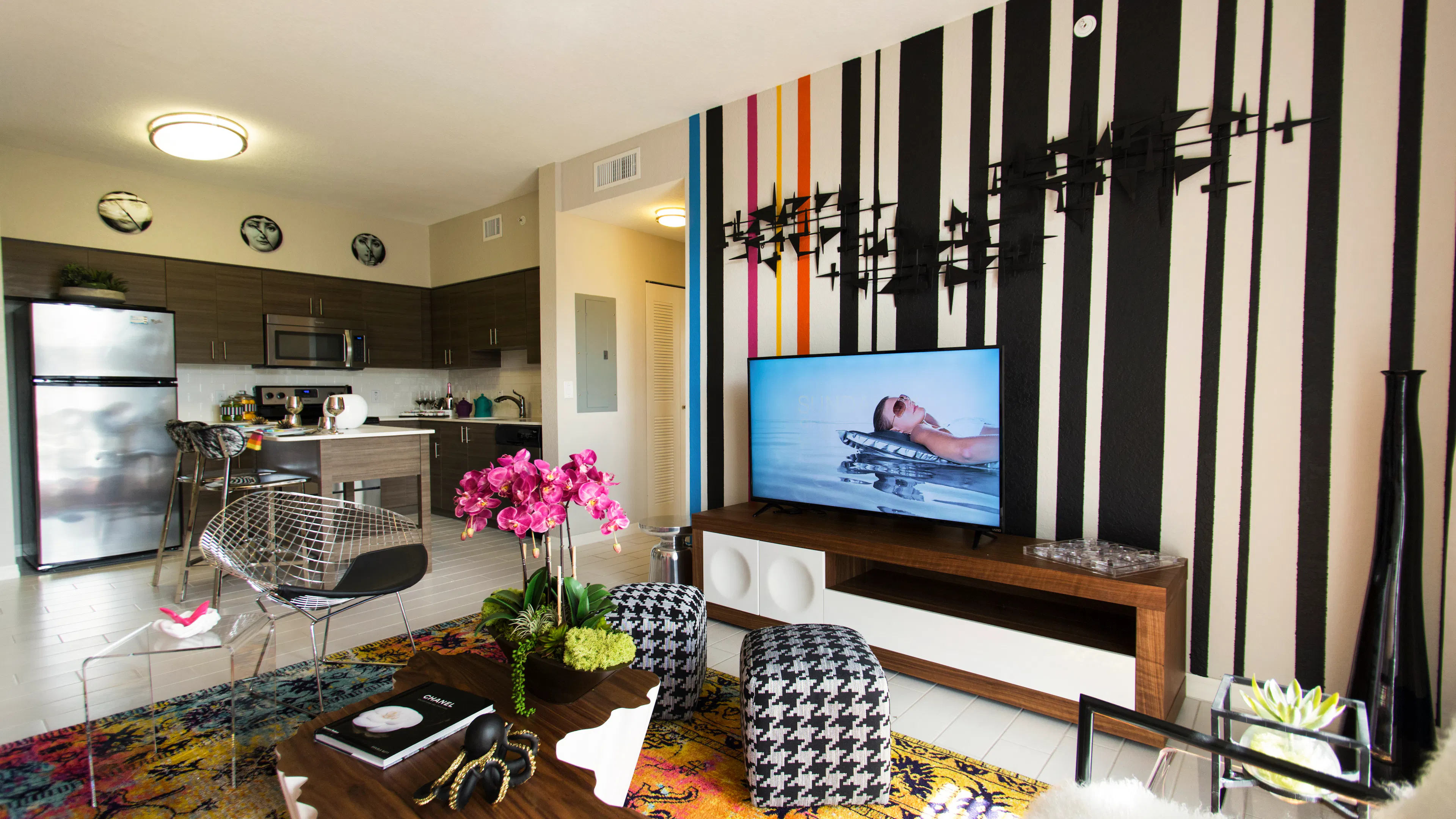 Interior of an AMLI Dadeland apartment living area with white sofa, pillows, modern colorful artwork and black floor lamps