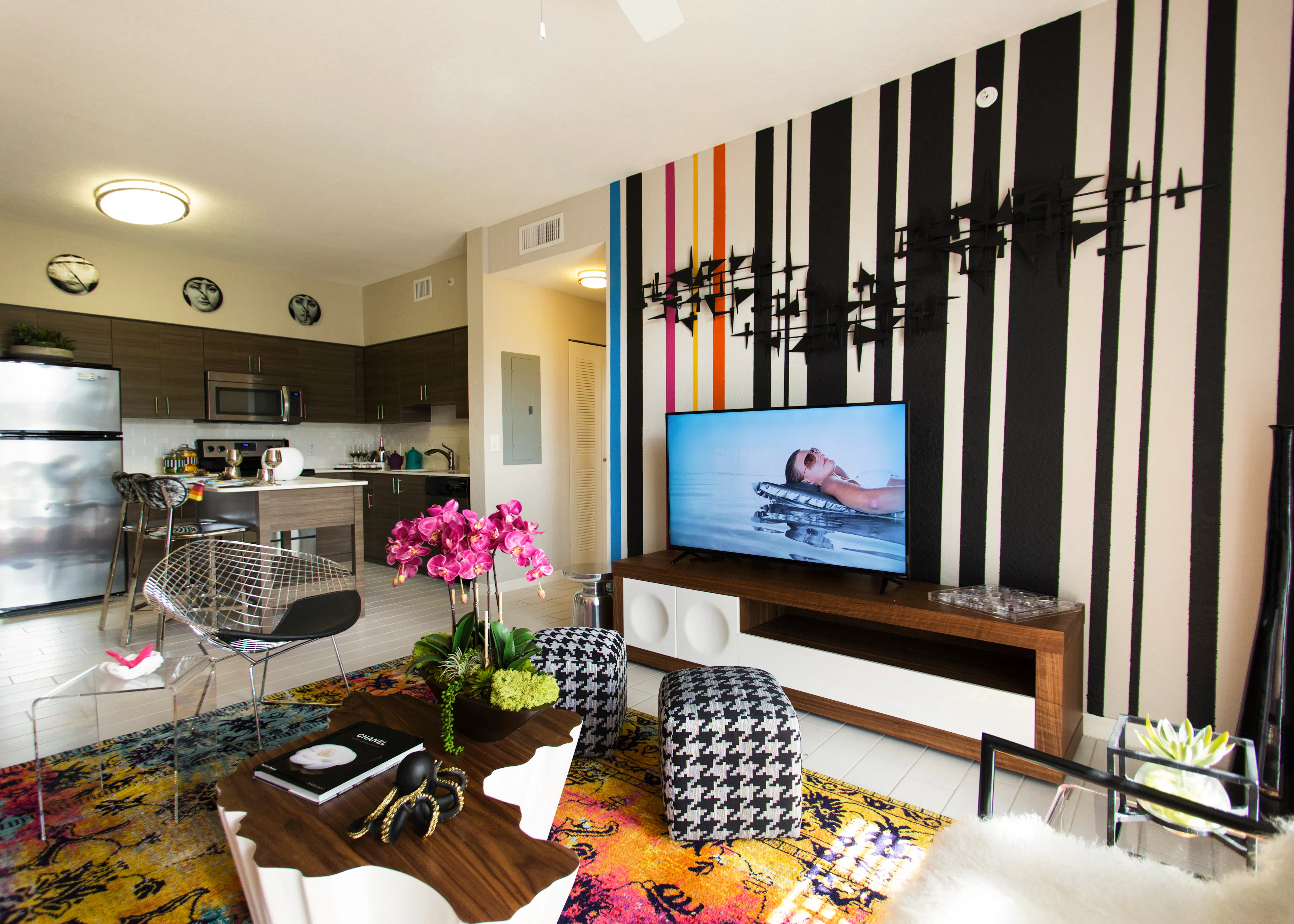 Interior of an AMLI Dadeland apartment living area with white sofa, pillows, modern colorful artwork and black floor lamps