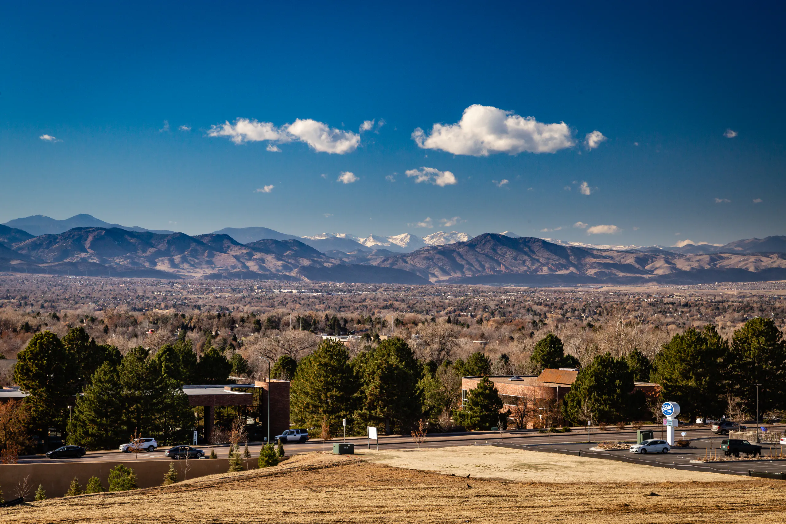 Panoramic view of nearby snow-capped Rocky mountains and Littleton neighborhood surrounding.