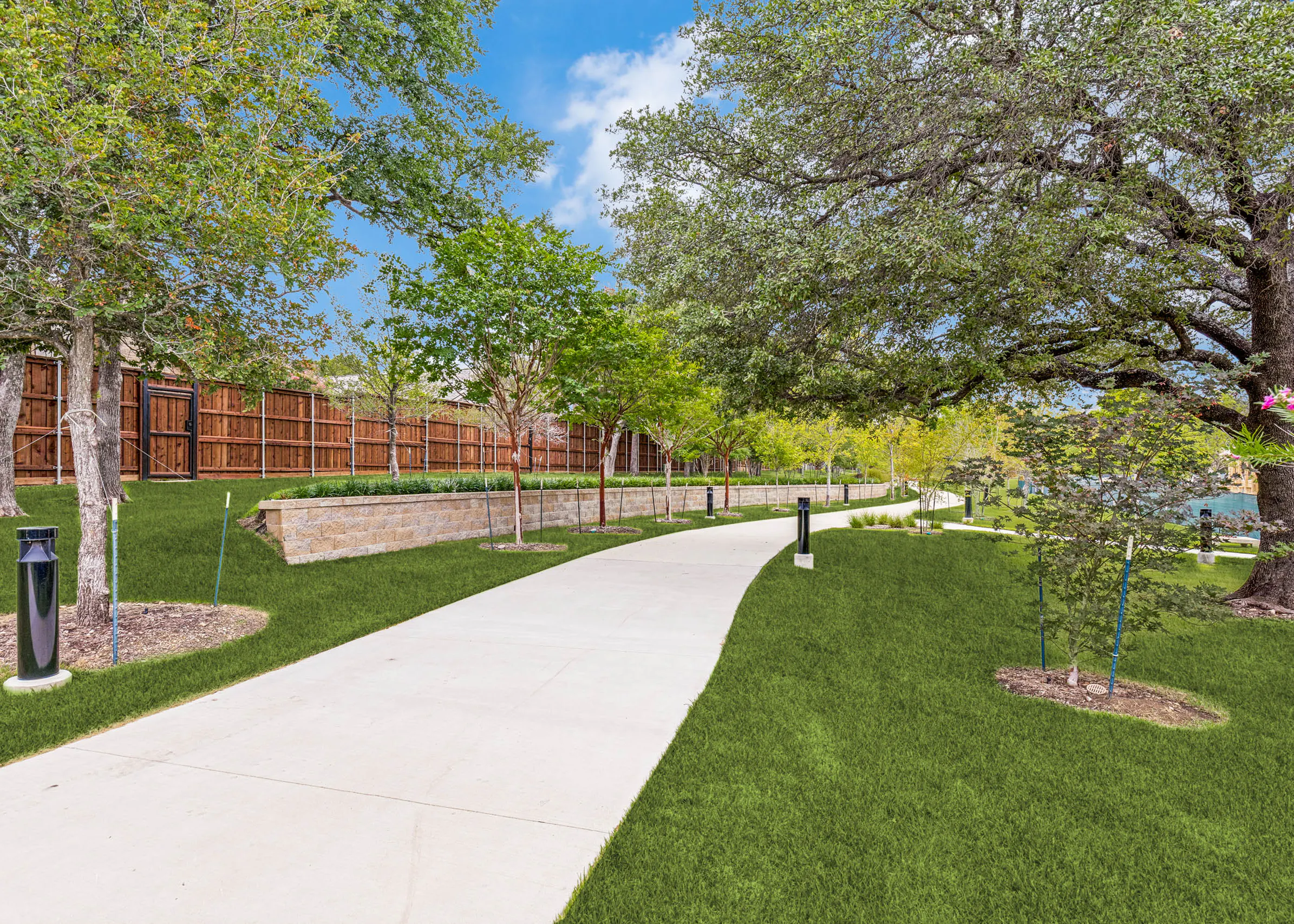 Landscaped walking trail with shaded green space, manicured lawn, retaining wall, pathway lighting, and lush greenery at AMLI Treehouse.