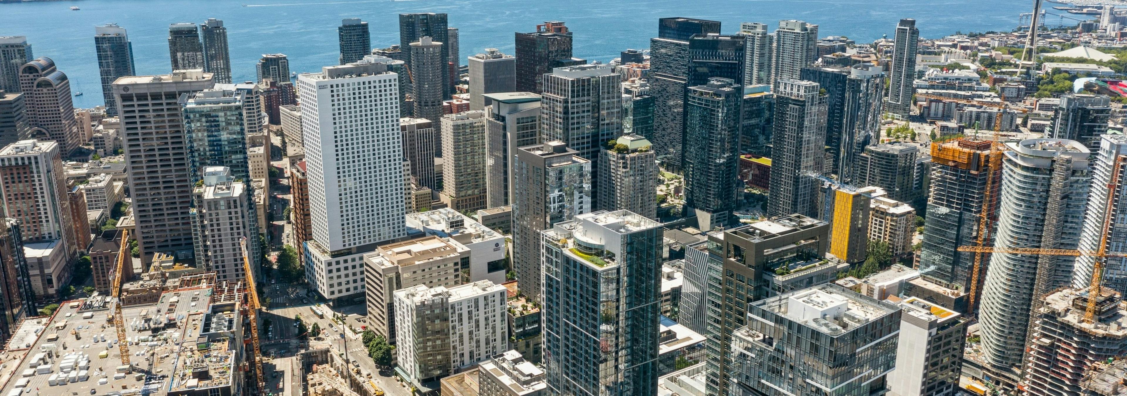 Aerial view of AMLI Arc high rise apartment building surrounded by other buildings with Seattle and the lake in the distance