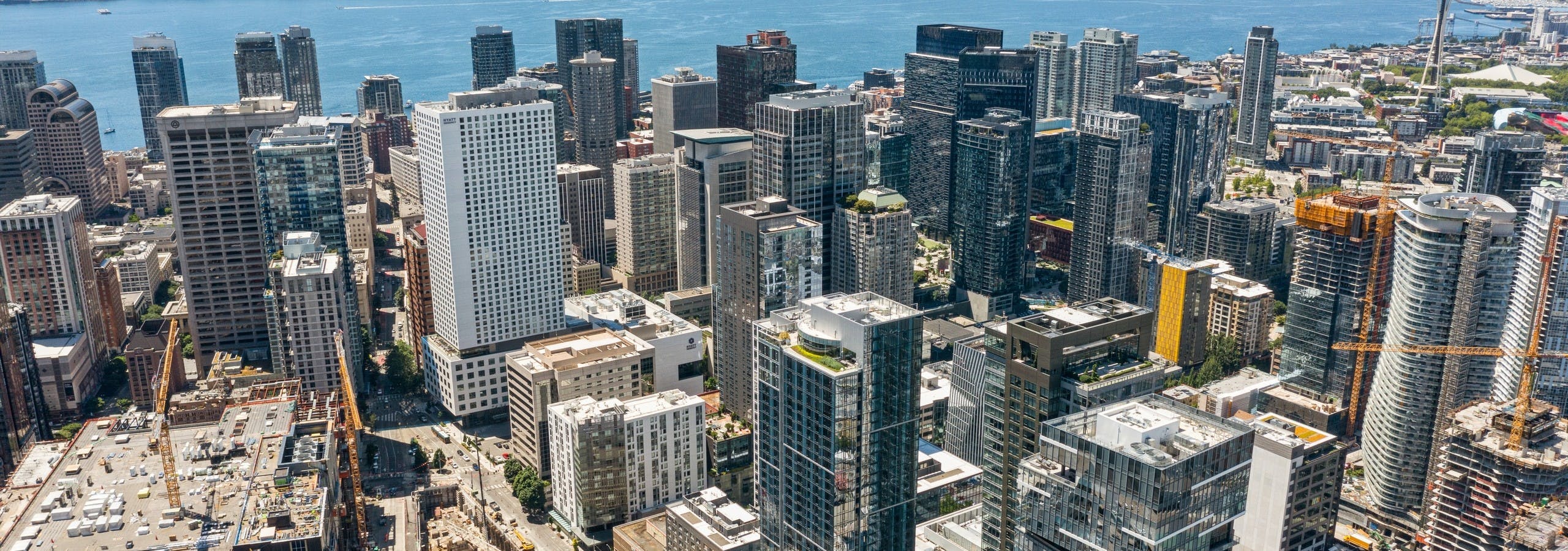 Aerial view of AMLI Arc high rise apartment building surrounded by other buildings with Seattle and the lake in the distance