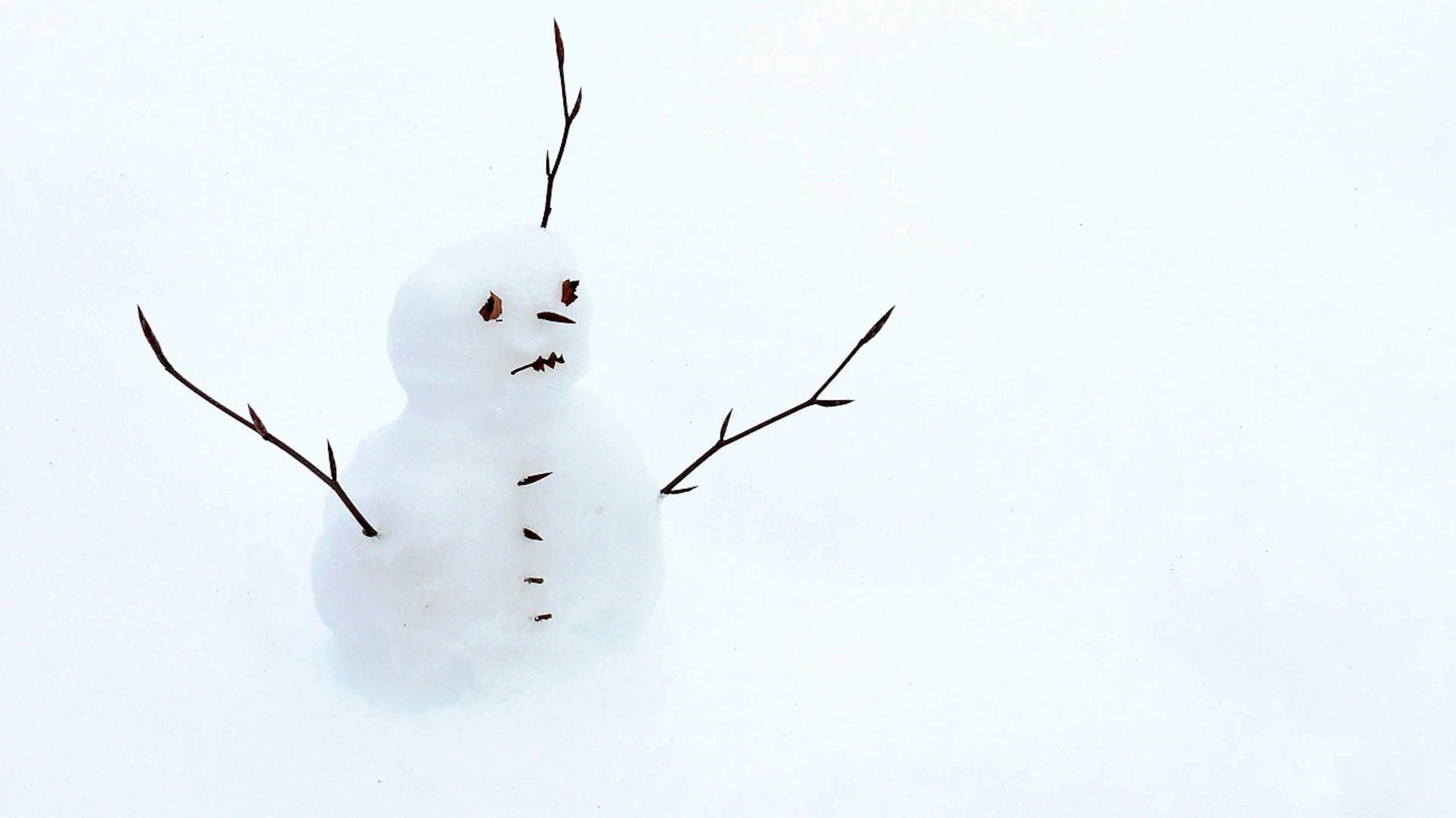 small sad faced snowman with stick arms and face
