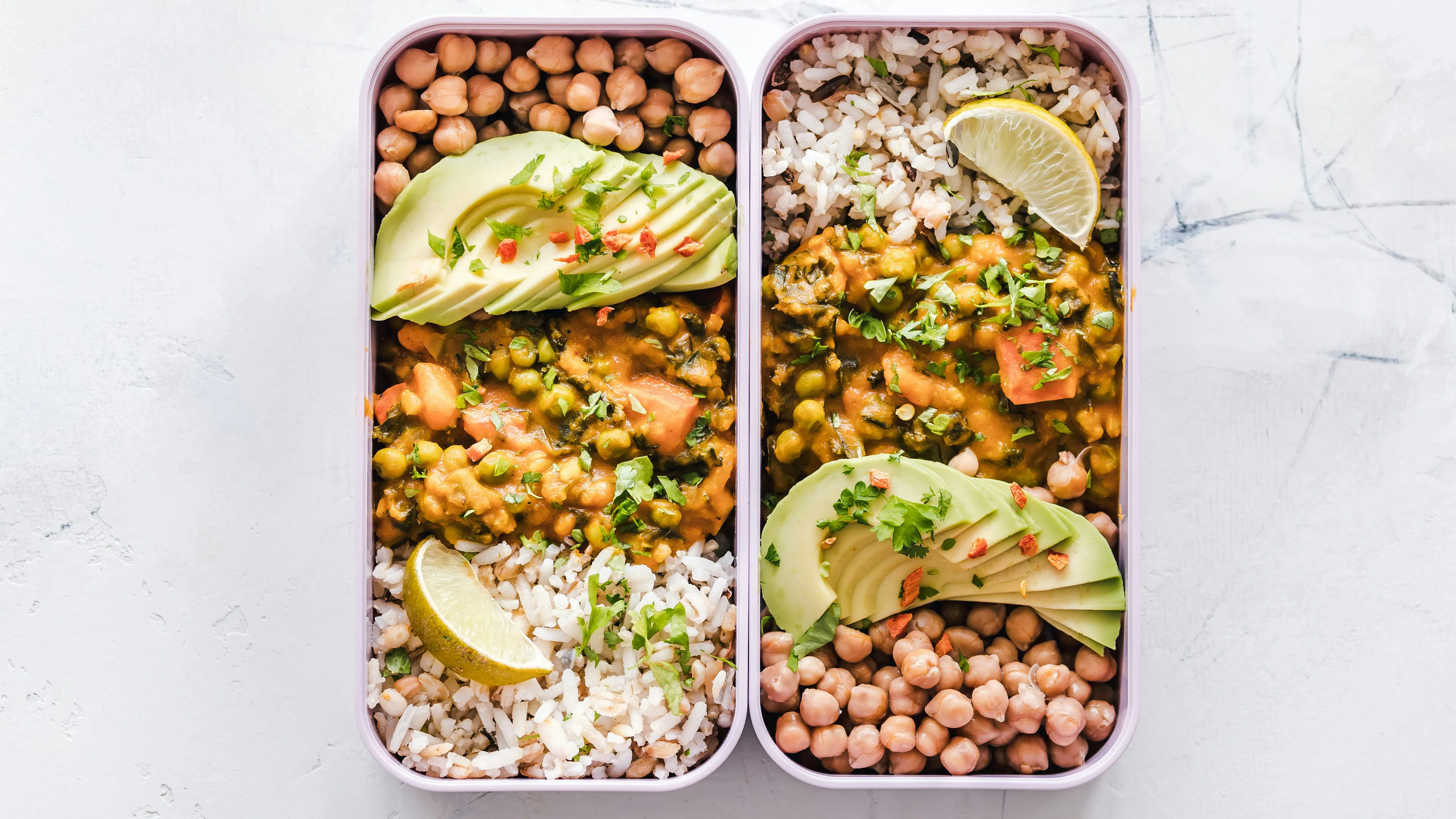 Two rectangle tupperware filled with roasted vegetables and avocado meal prep