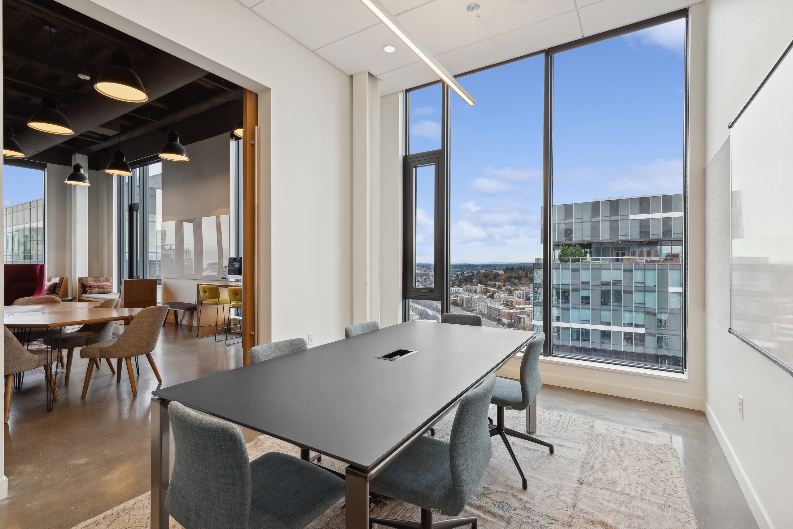Conference room at AMLI Arc apartments with a sleek black table, upholstered chairs, floor to ceiling windows and a view of the cityscape.