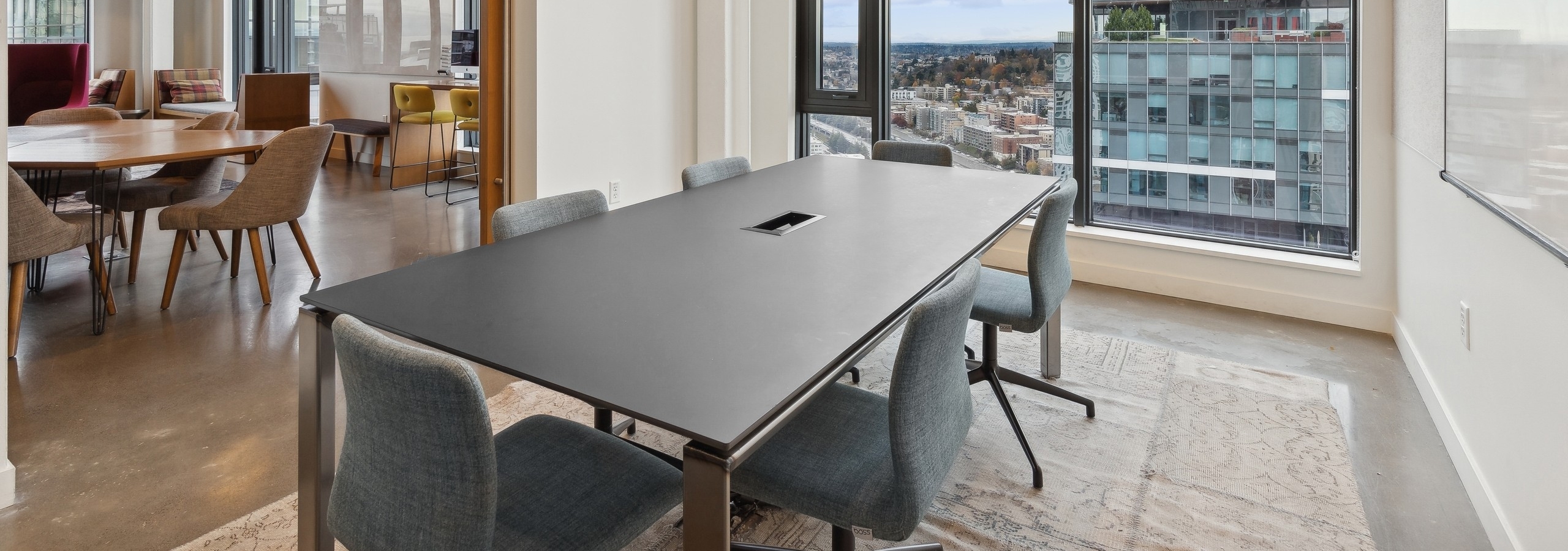 Conference room at AMLI Arc apartments with a sleek black table, upholstered chairs, floor to ceiling windows and a view of the cityscape.