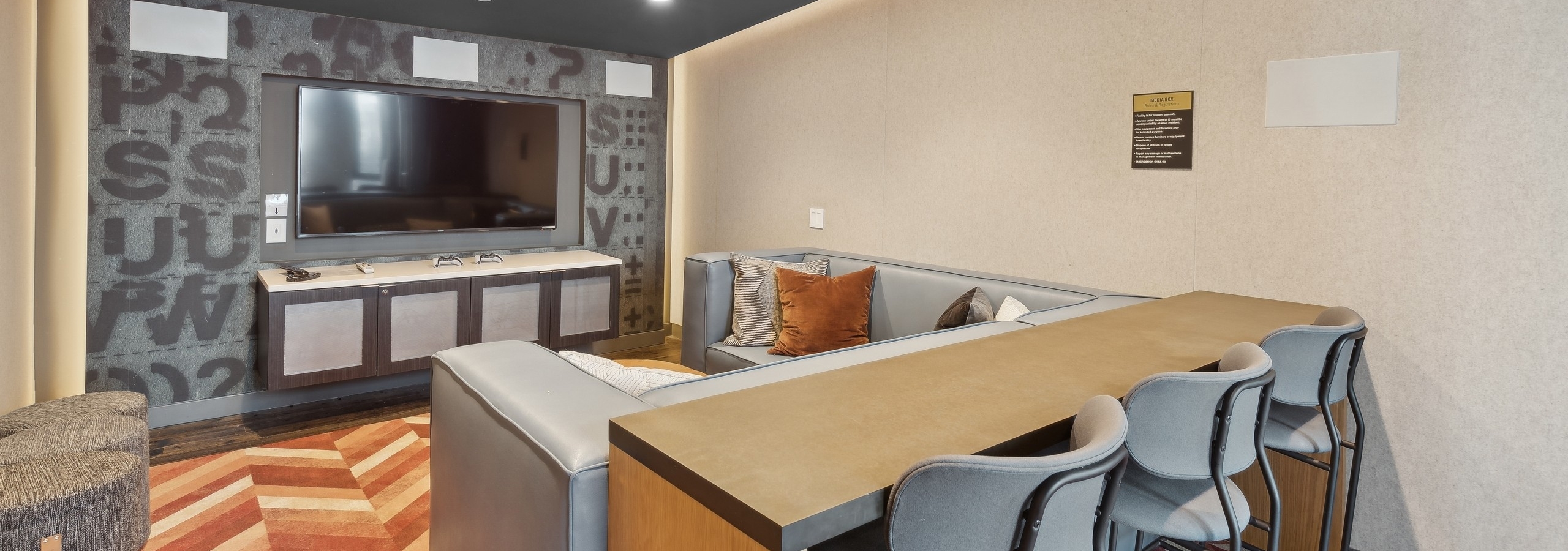 Media room at AMLI Arc with a large flat-screen TV, plush sectional seating, barstools at a hightop counter