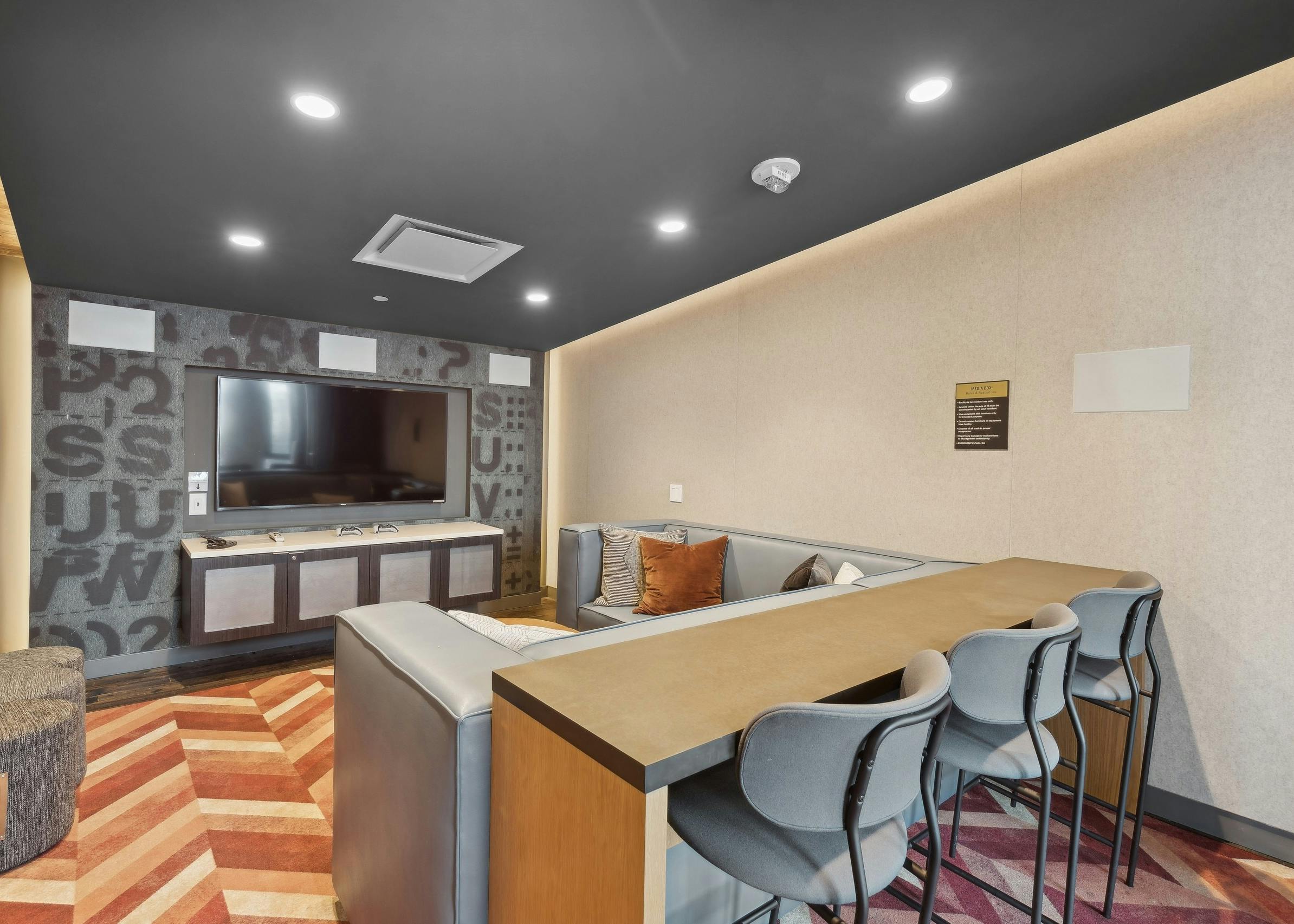 Media room at AMLI Arc with a large flat-screen TV, plush sectional seating, barstools at a hightop counter