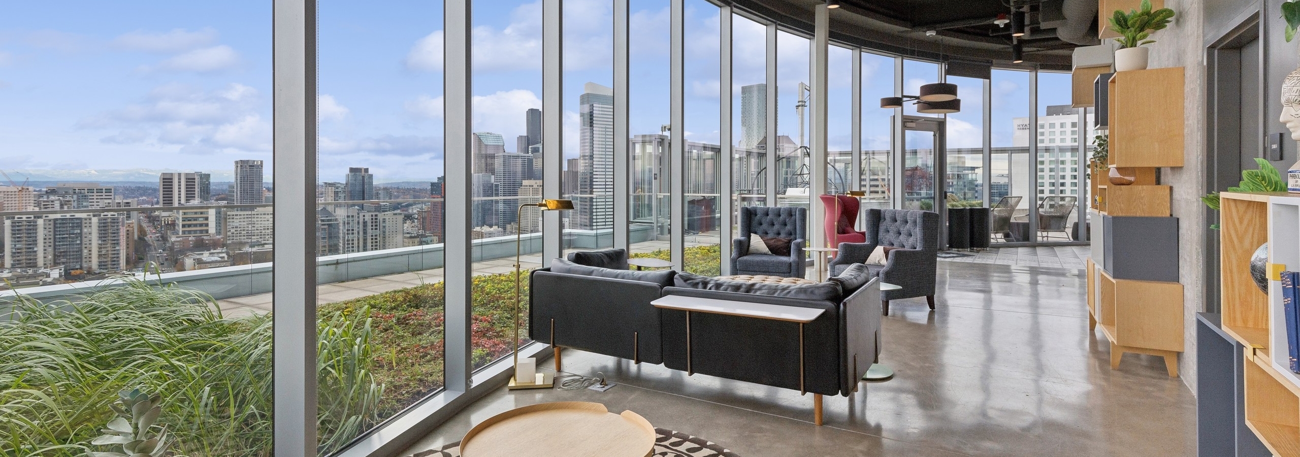 Edge lounge at AMLI Arc with floor-to-ceiling windows, modern seating and panoramic views of the downtown skyline and greenery.