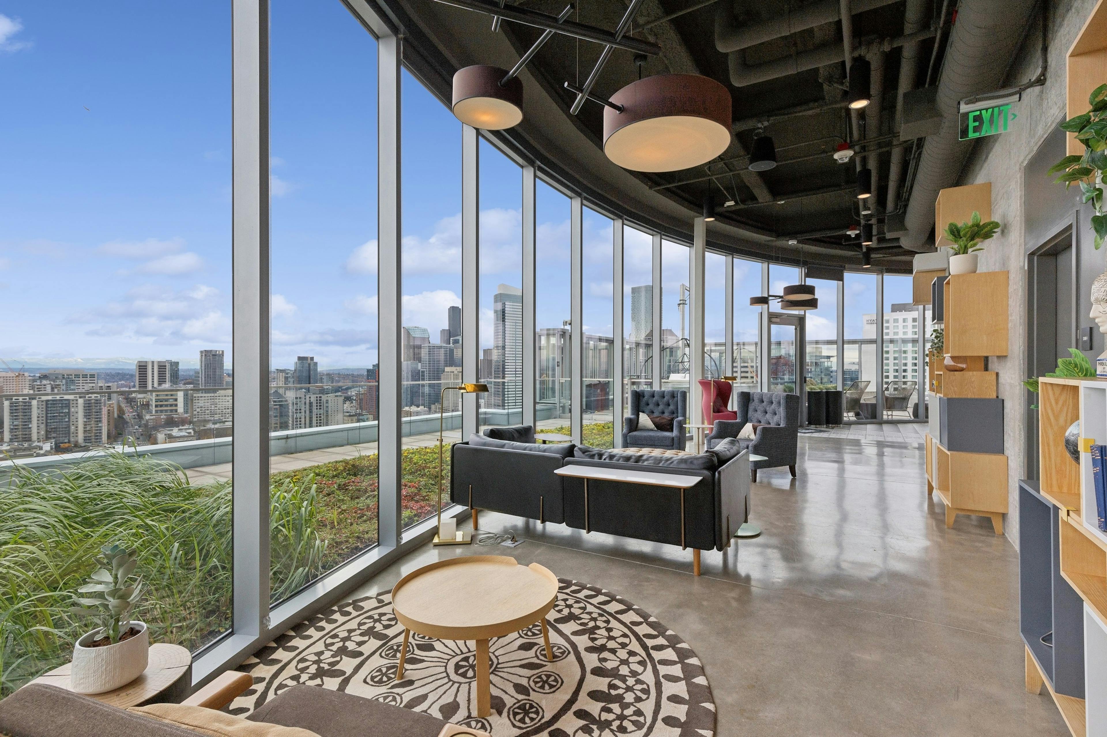 Edge lounge at AMLI Arc with floor-to-ceiling windows, modern seating and panoramic views of the downtown skyline and greenery.
