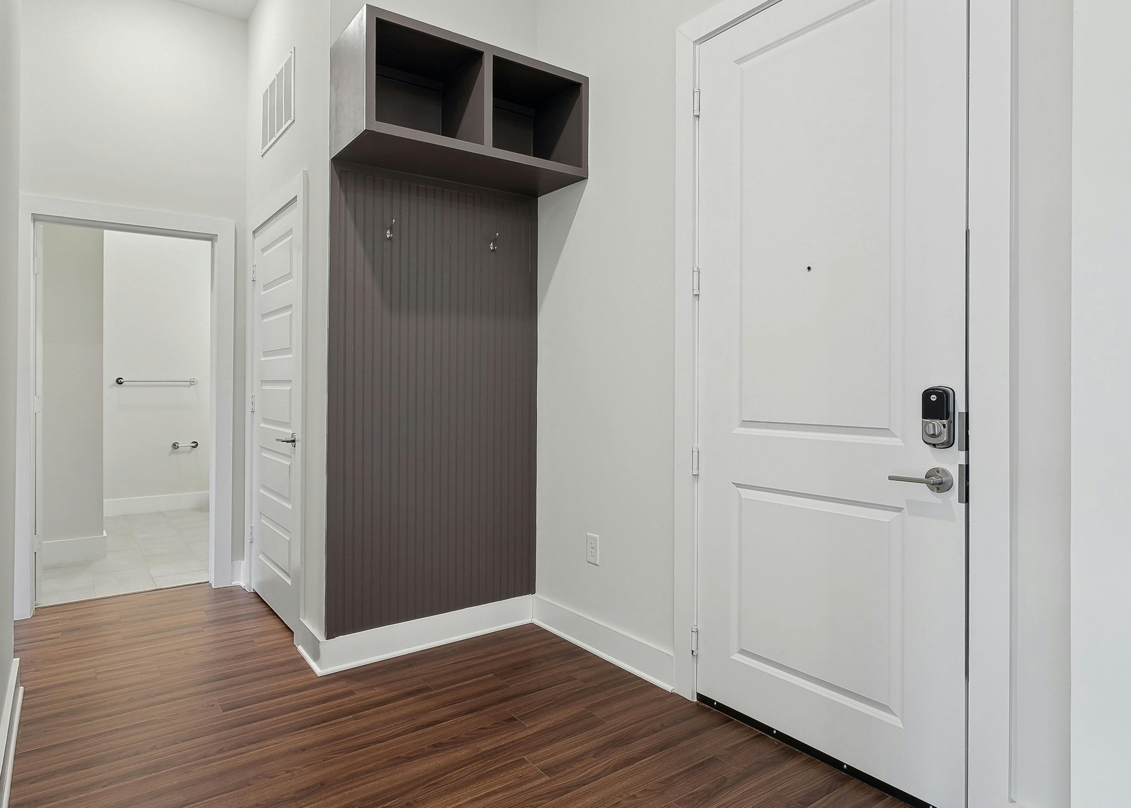 Mudroom area with gray wall with coat hooks and cubbies above adjacent to the front door at AMLI Brookhaven apartments