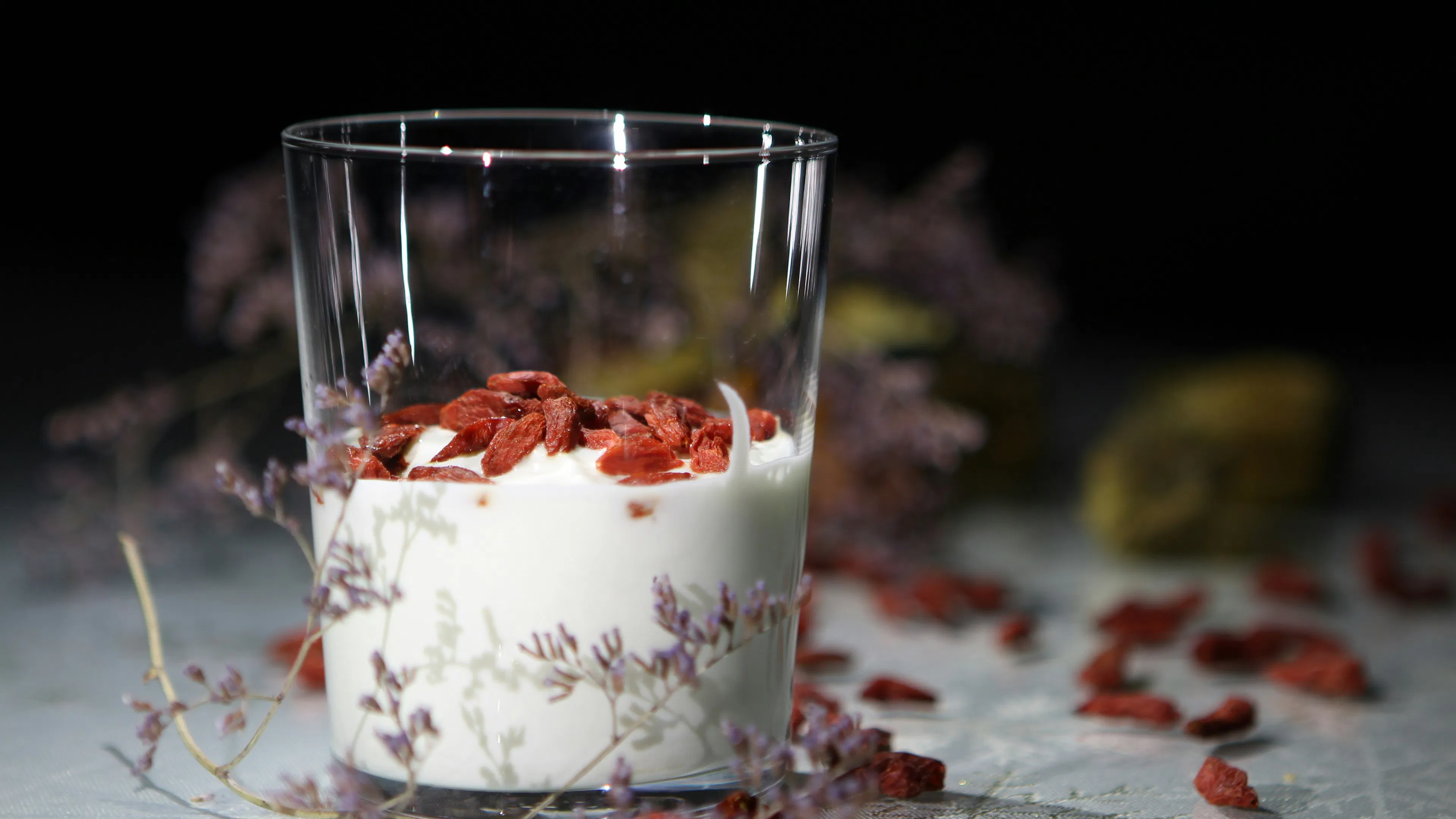 A glass container filled with plain yogurt and topped with red berries