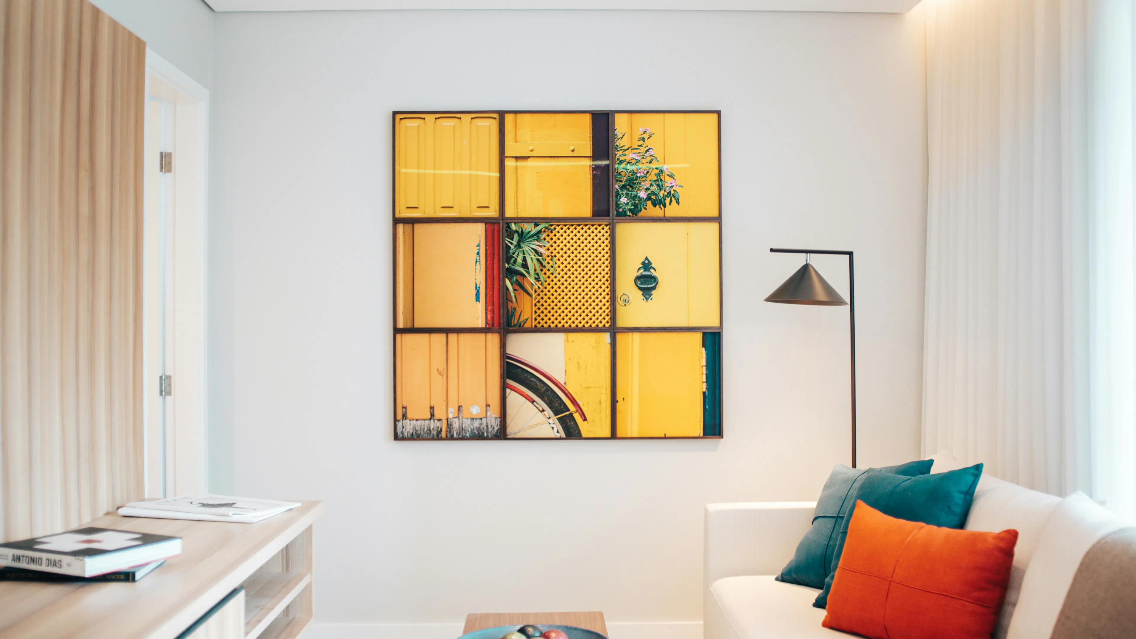 A white walled apartment room with a 9 square image collage of yellow paints and textures on the wall