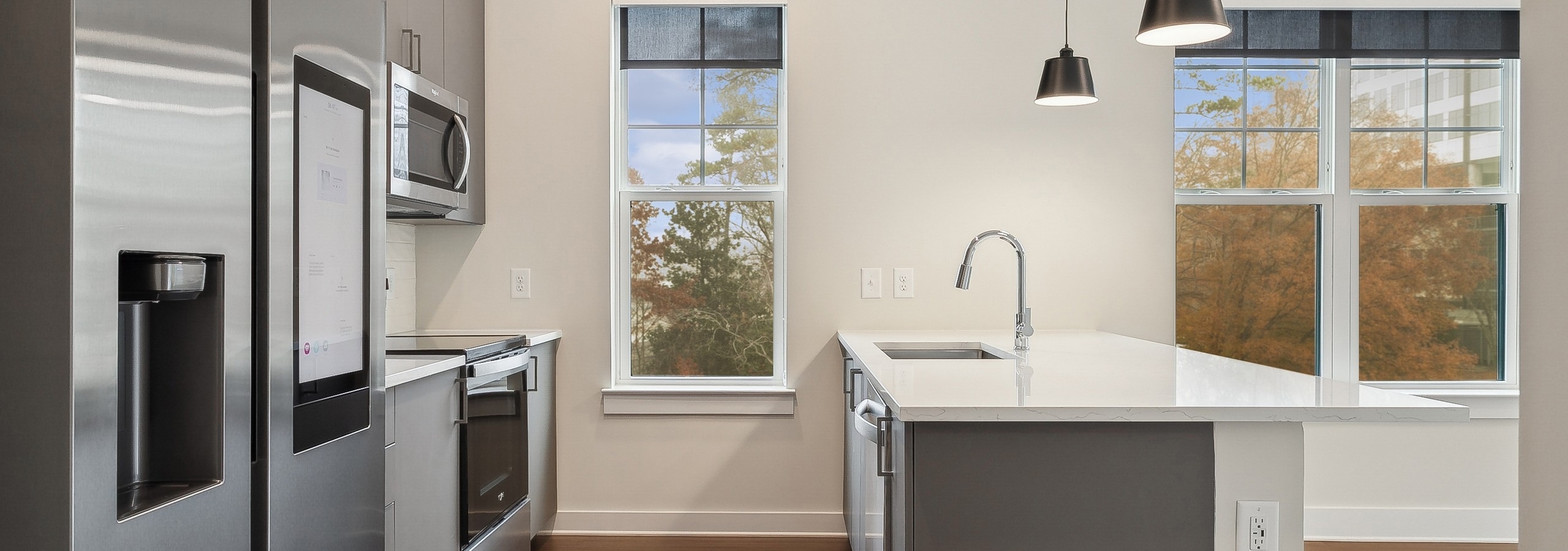 Interior view of a kitchen at AMLI Brookhaven with large white peninsula island, stainless steel appliances and 2 windows