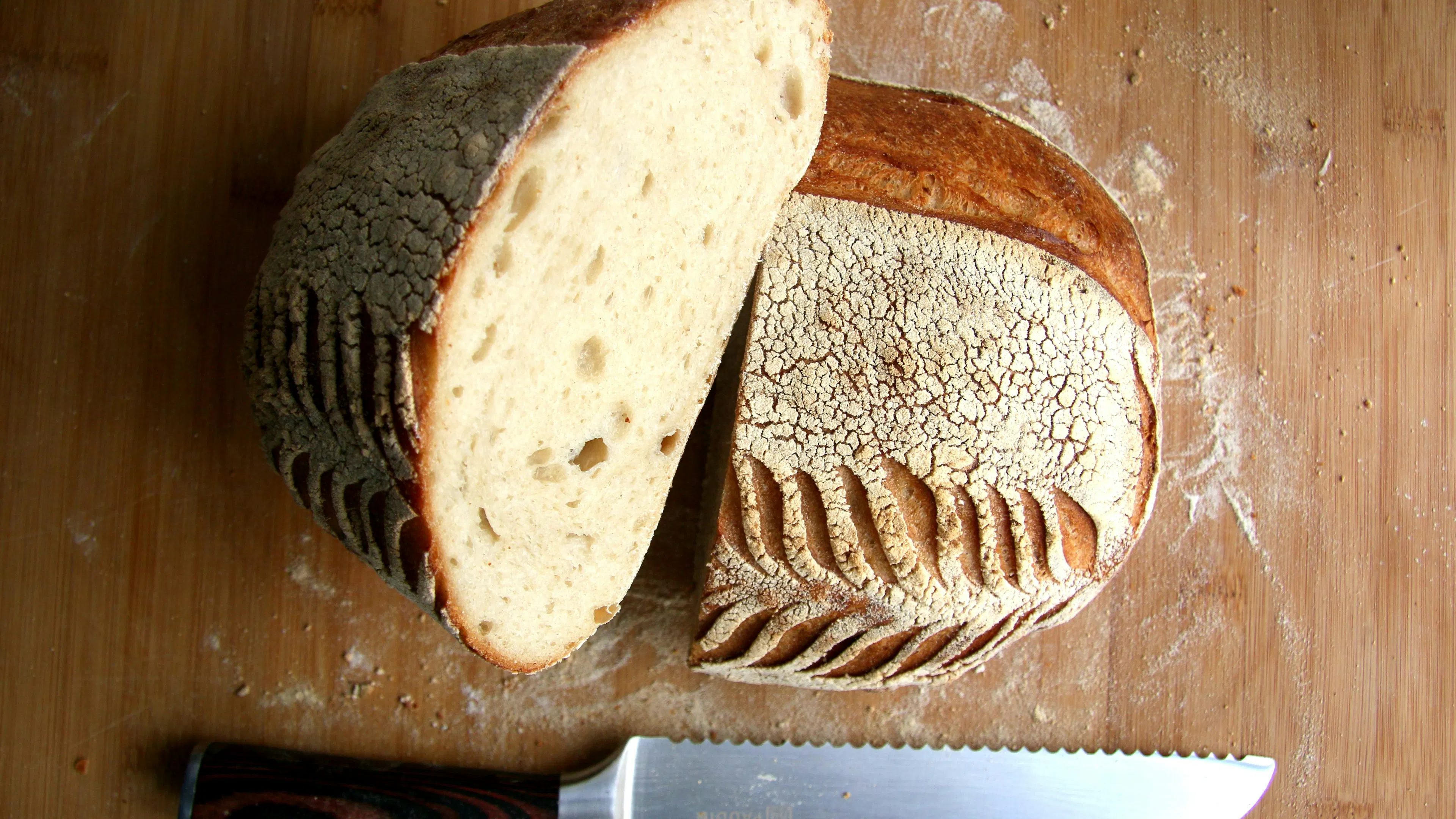 A loaf of sourdough bread sliced in half and displayed on a wooden table