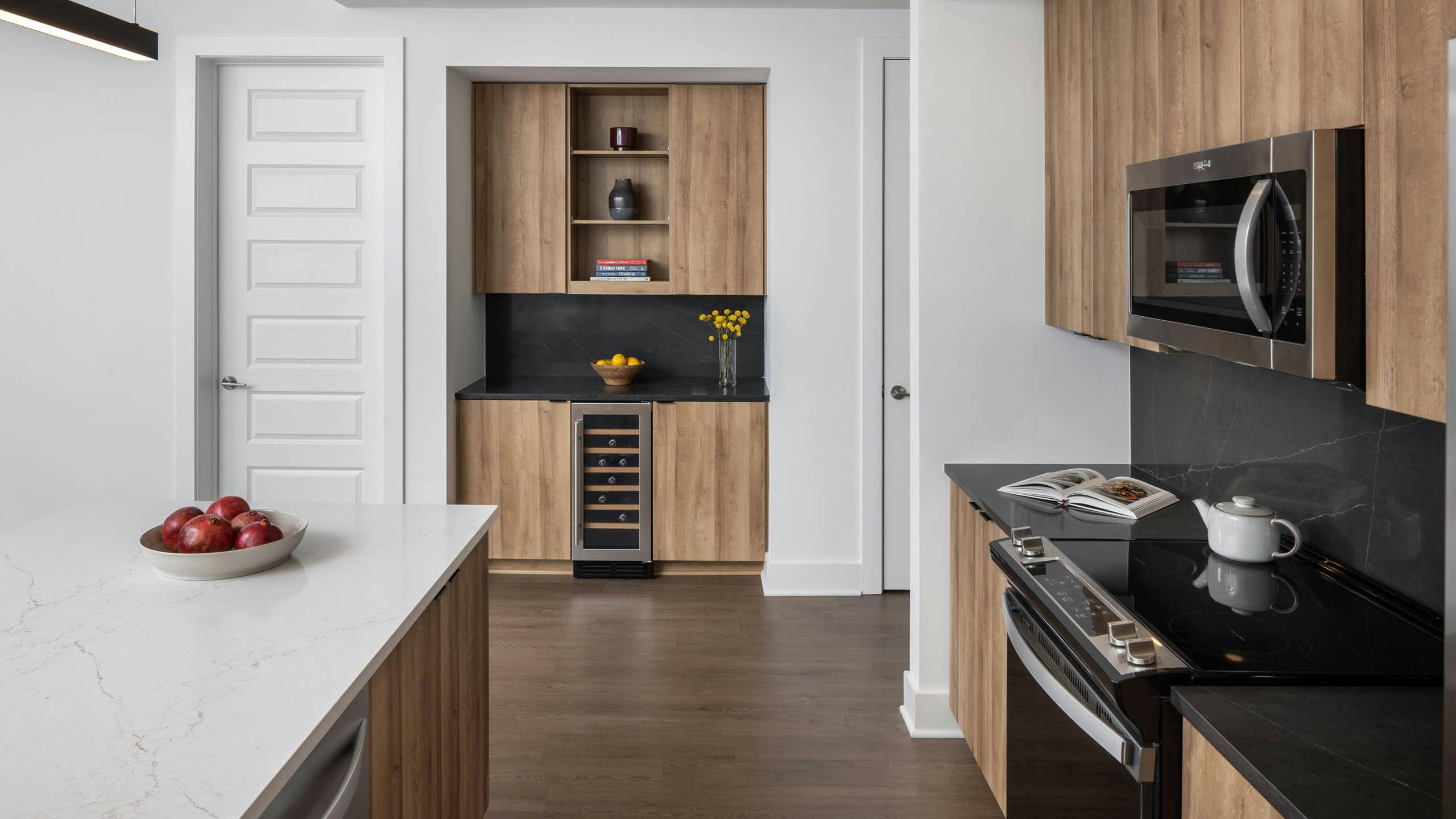 Kitchen and bar area with black and white counters at AMLI Atlantic Station showing a wine refrigerator and stainless steel appliances