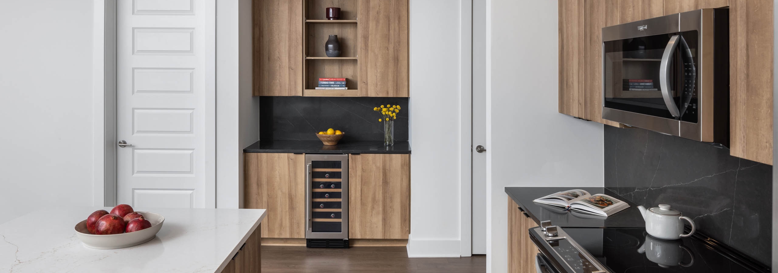 Kitchen and bar area with black and white counters at AMLI Atlantic Station showing a wine refrigerator and stainless steel appliances