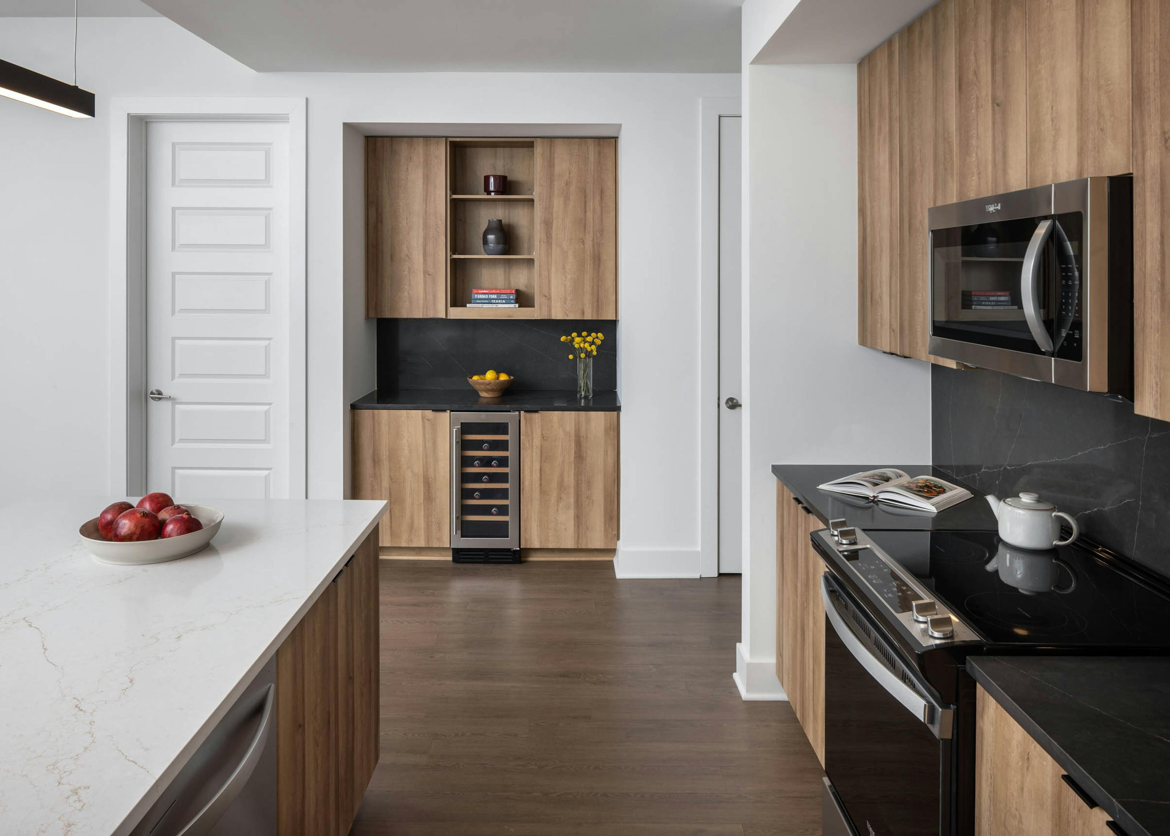 Kitchen and bar area with black and white counters at AMLI Atlantic Station showing a wine refrigerator and stainless steel appliances