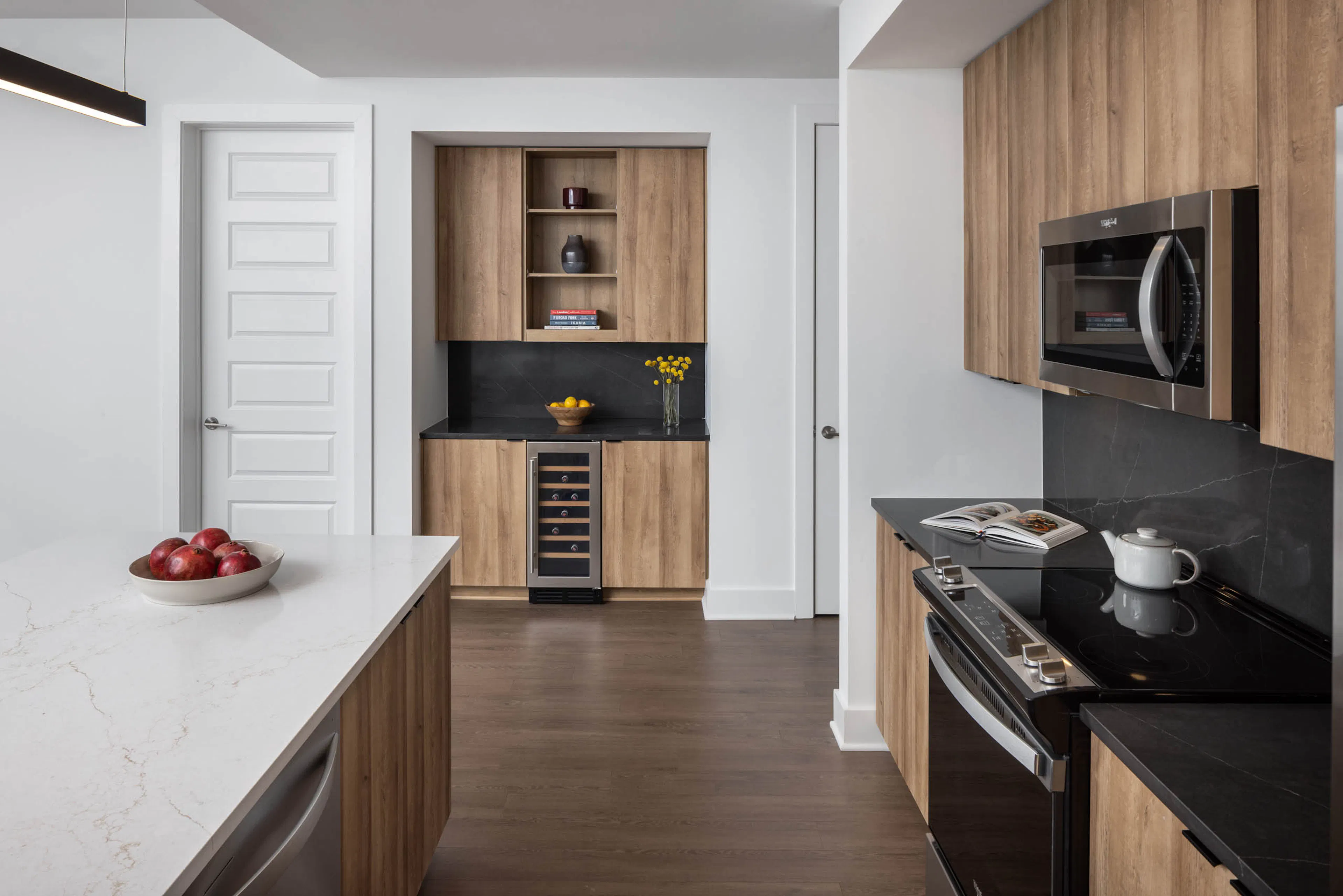 Kitchen and bar area with black and white counters at AMLI Atlantic Station showing a wine refrigerator and stainless steel appliances