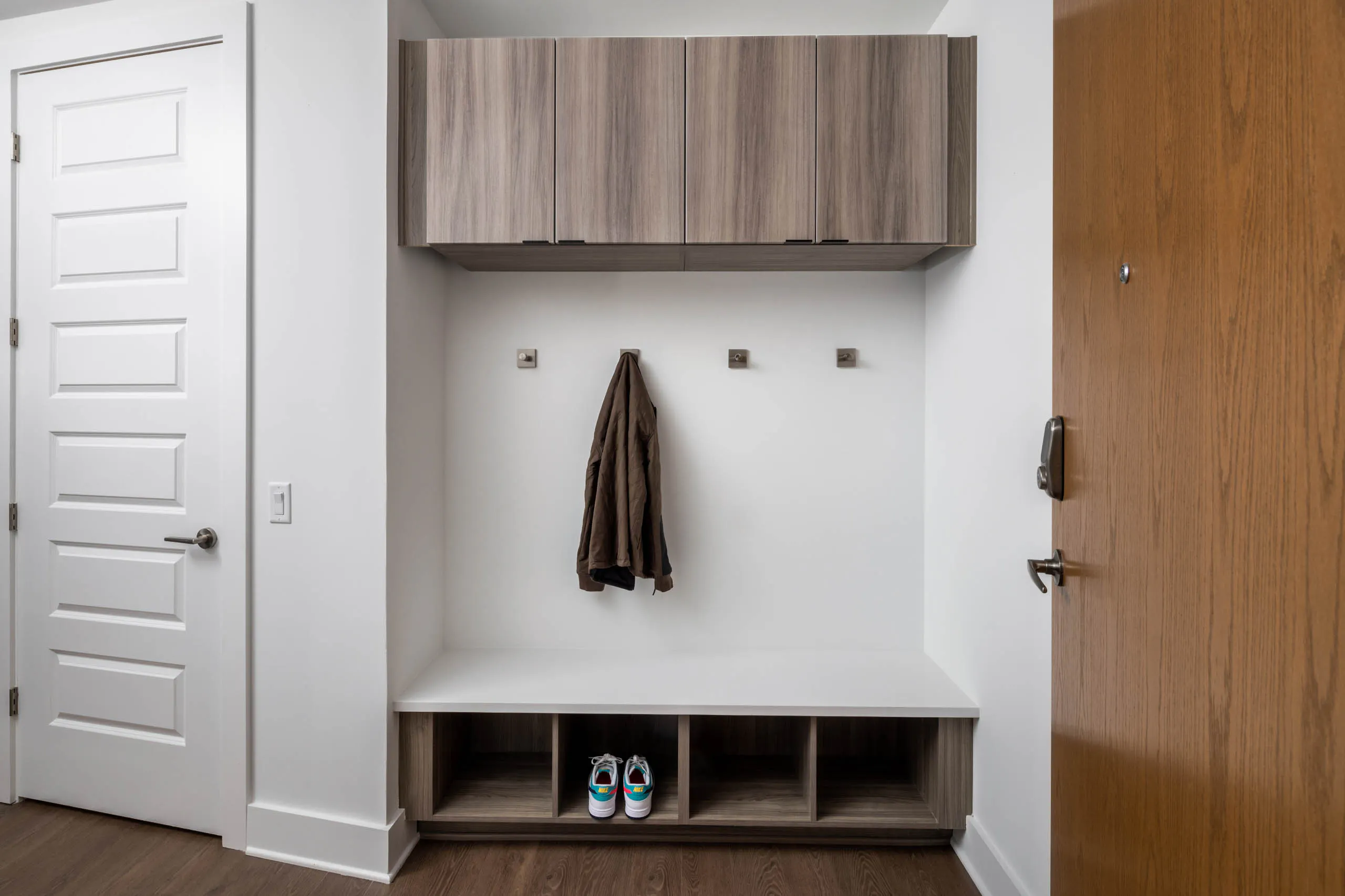 Hallway entry with at AMLI Atlantic Station apartments showing a mudroom with square coat hooks, storage and a jacket with a pair of sneakers.