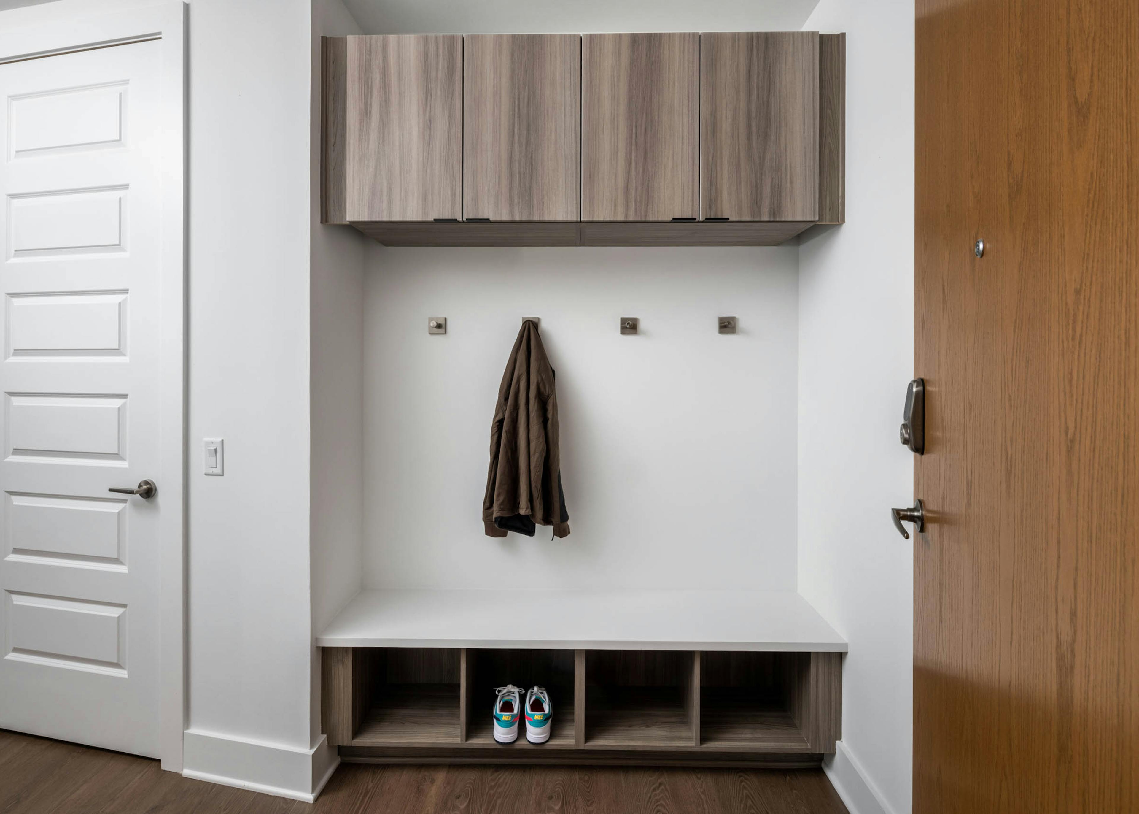 Hallway entry with at AMLI Atlantic Station apartments showing a mudroom with square coat hooks, storage and a jacket with a pair of sneakers.