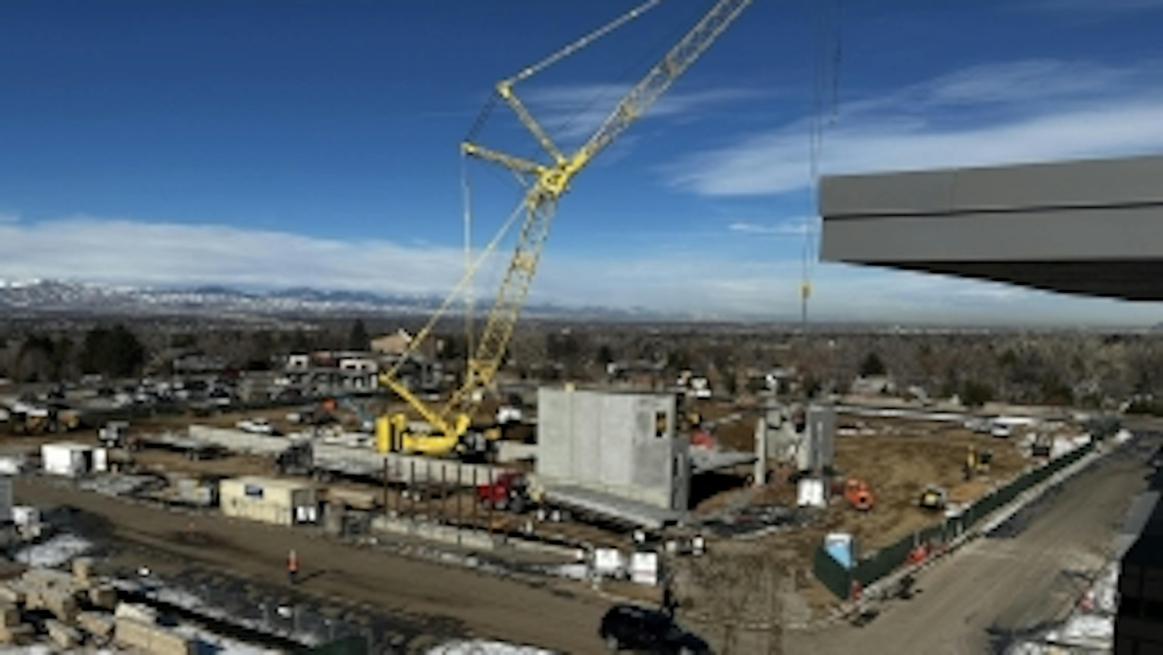 Construction site with equipment surrounding a large yellow crane and concrete walls at AMLI Village Park apartments