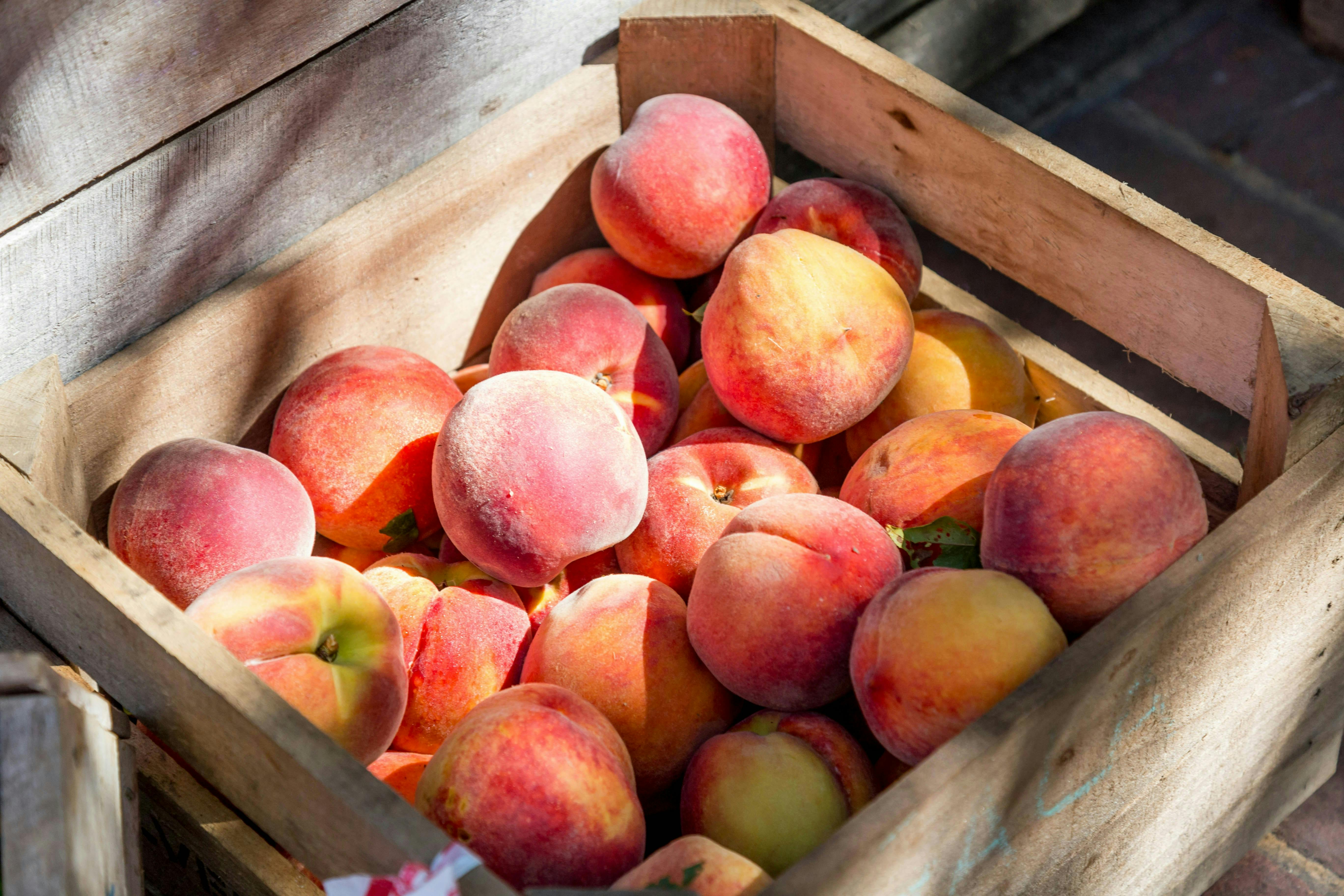 A wooden crate filled with peaches