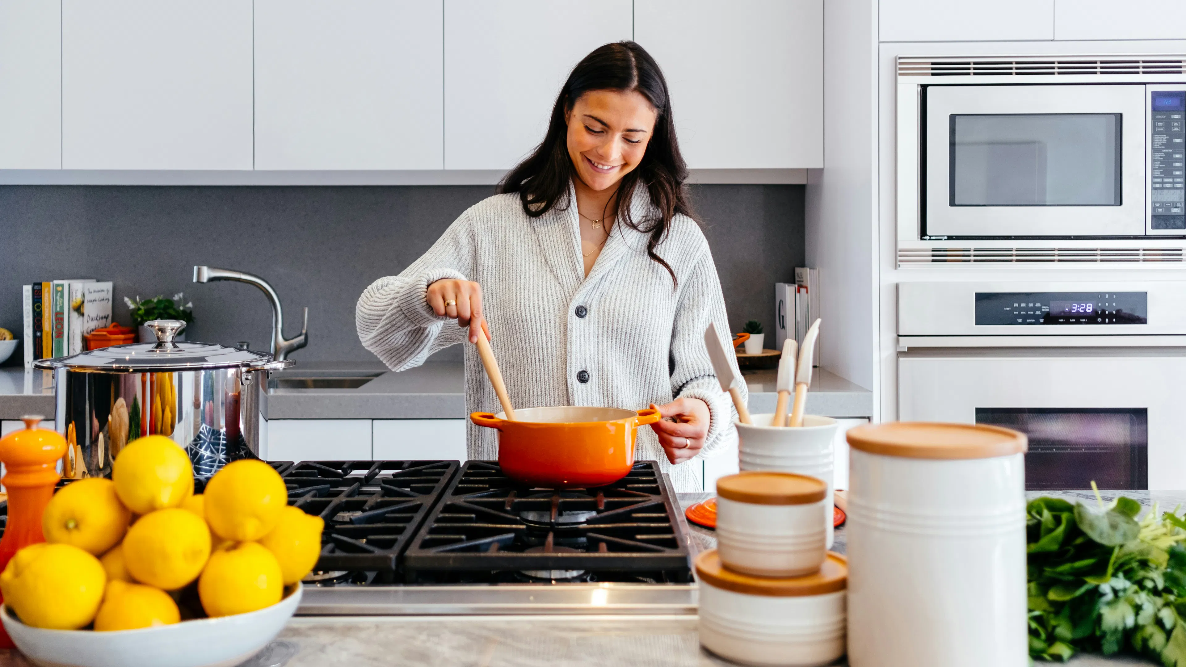 A woman stirring a stew in an orange pot on a stove