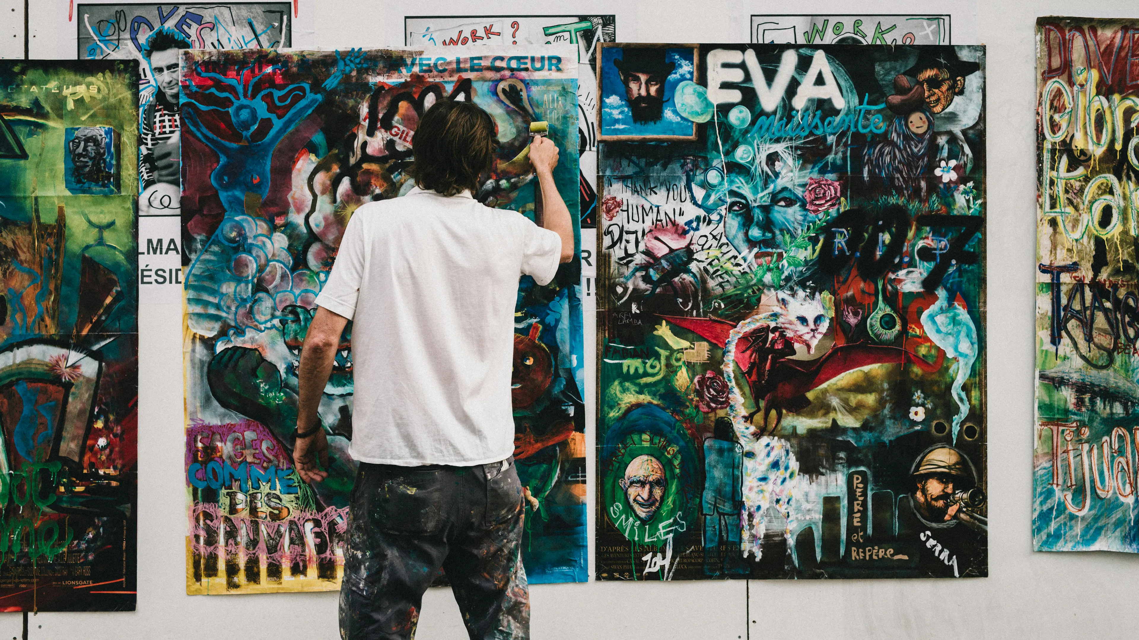 an artist painting three graffiti art canvases