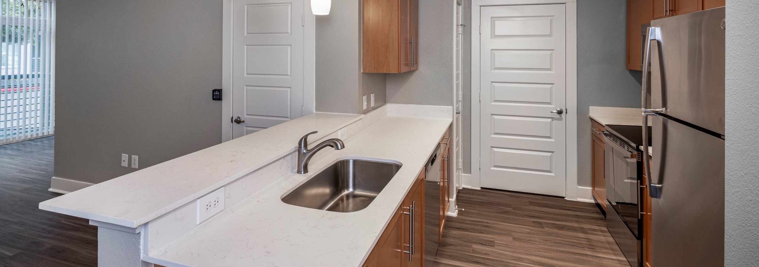 AMLI South Shore kitchen with white quartz countertops and light wood cabinets with stainless steel appliances