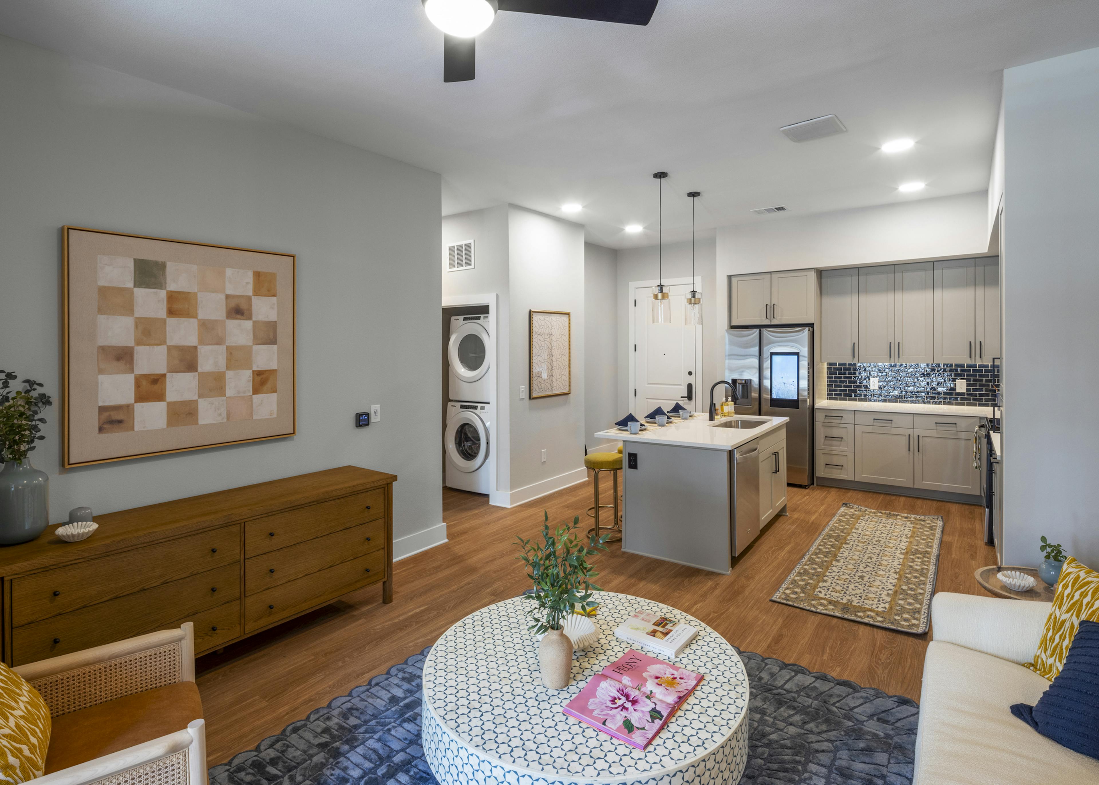 Interior view of an open-concept living area at AMLI North Park with a modern kitchen with a blue tile backsplash, and in-unit laundry
