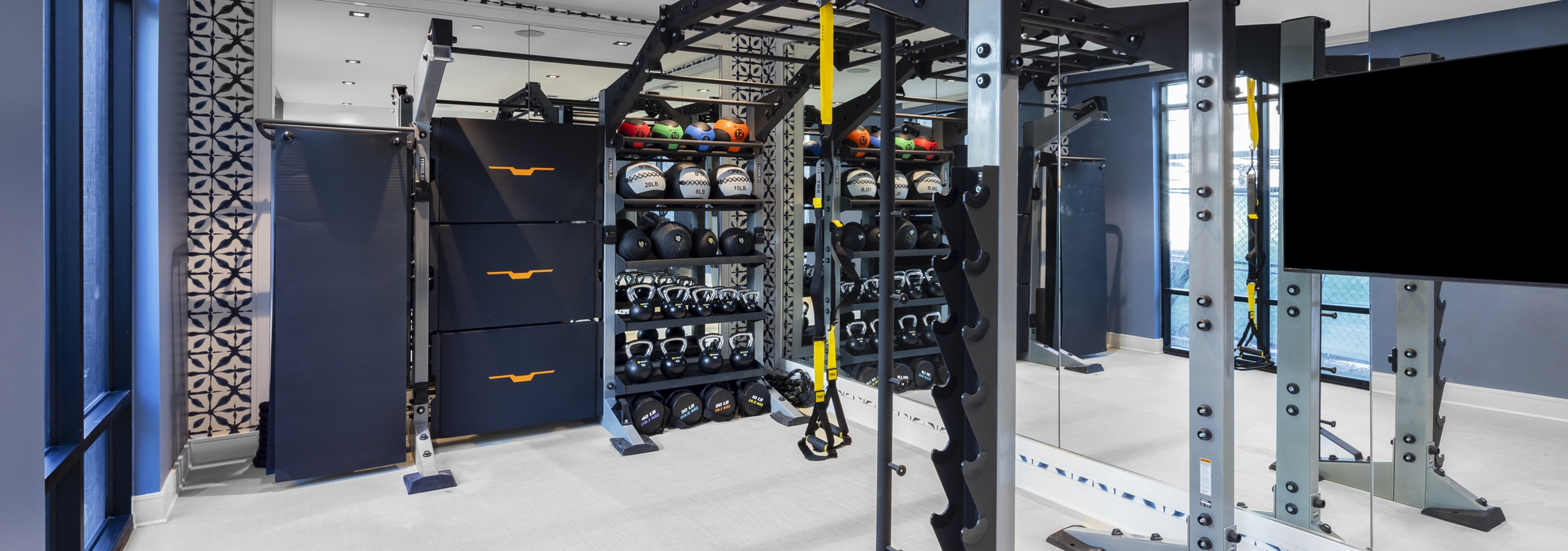 Functional training area at AMLI North Park with free weights, resistance bands, squat racks, and a mirrored wall for workouts