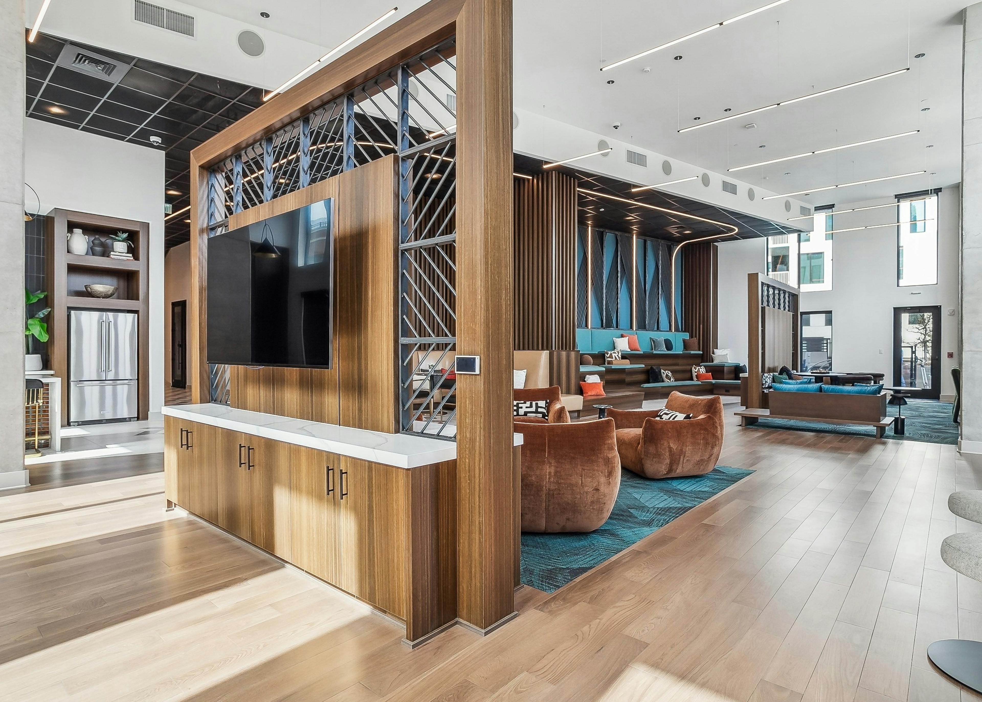 Interior view of a lounge area at AMLI Atlantic Station with wooden floors and accents and featuring plush seating and vibrant teal decor