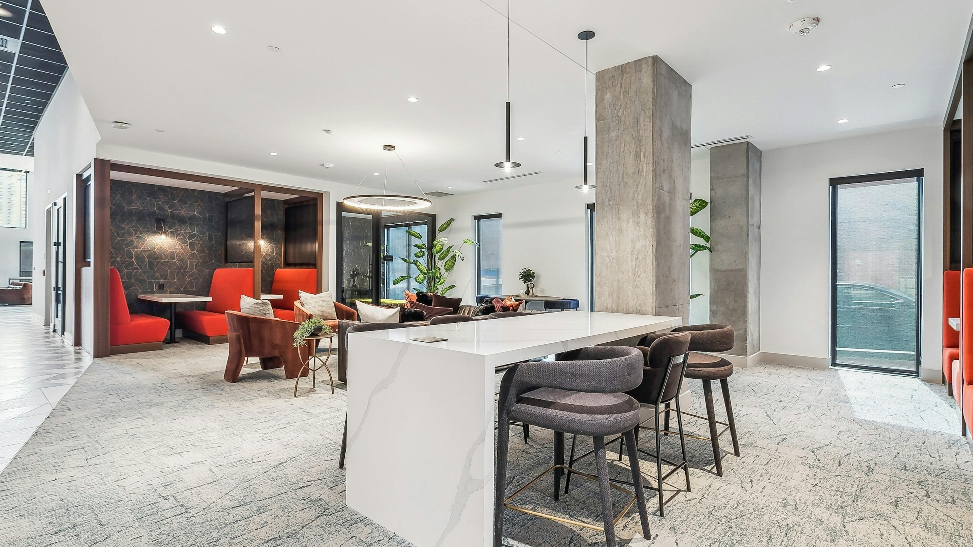 Coworking space at AMLI Atlantic Station with a long white table and several bar stools and a pendant light and red booths