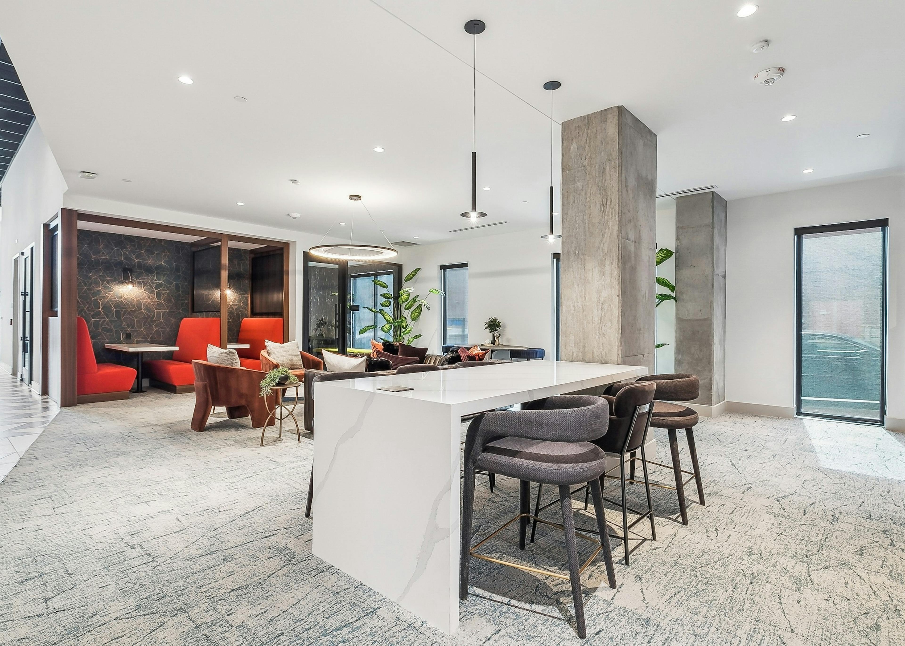 Coworking space at AMLI Atlantic Station with a long white table and several bar stools and a pendant light and red booths