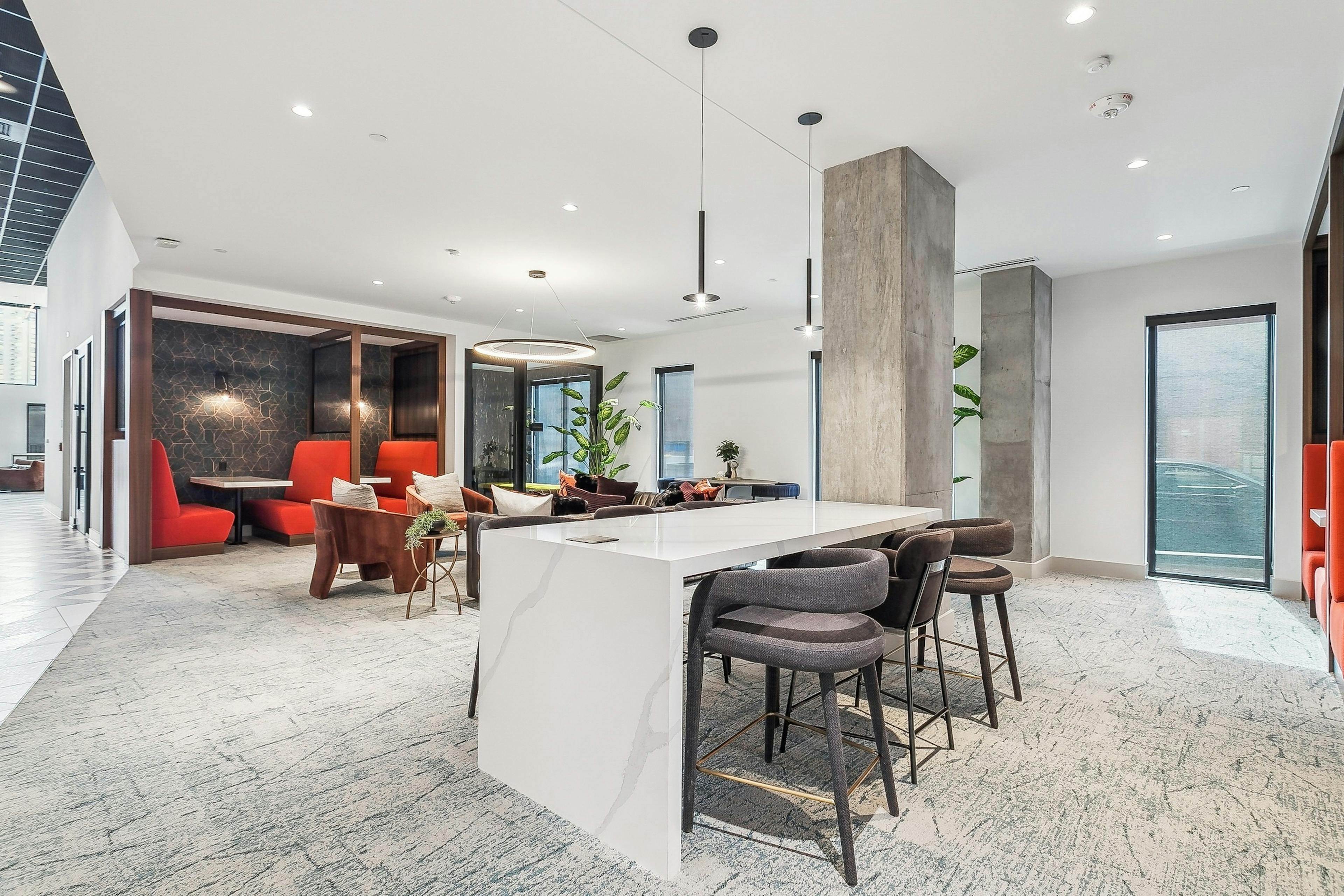 Coworking space at AMLI Atlantic Station with a long white table and several bar stools and a pendant light and red booths