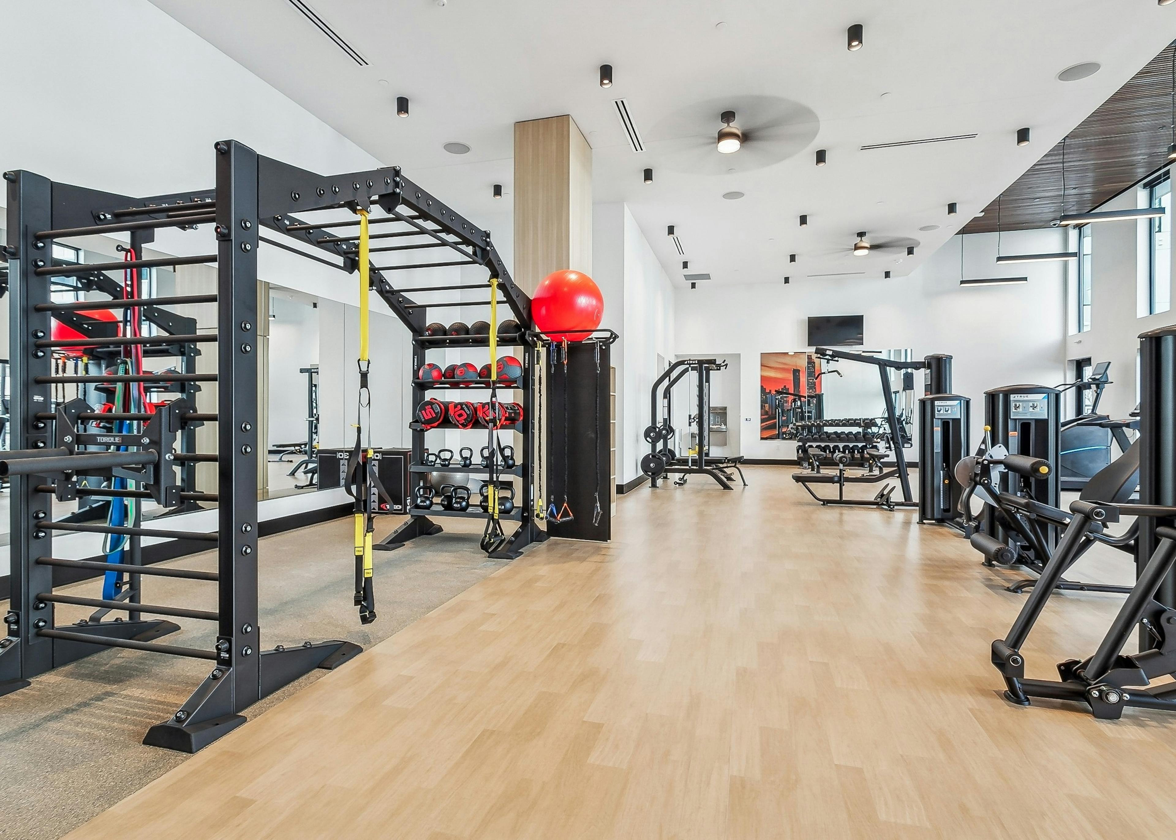 Fitness center at AMLI Atlantic Station with hardwood flooring and various strength training and cardio equipment 