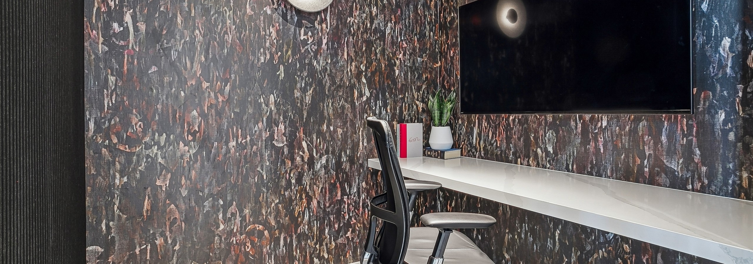 AMLI Atlantic Station private office space with an chair at a desk and a large screen mounted on patterned dark wallpaper